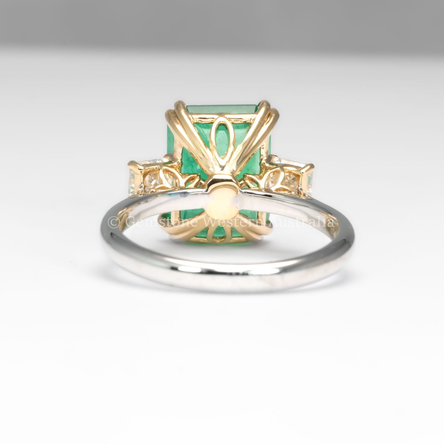 back view of Colombian Emerald and Diamond Ring in 18K Yellow Gold – East West Emerald Cut in neutral background
