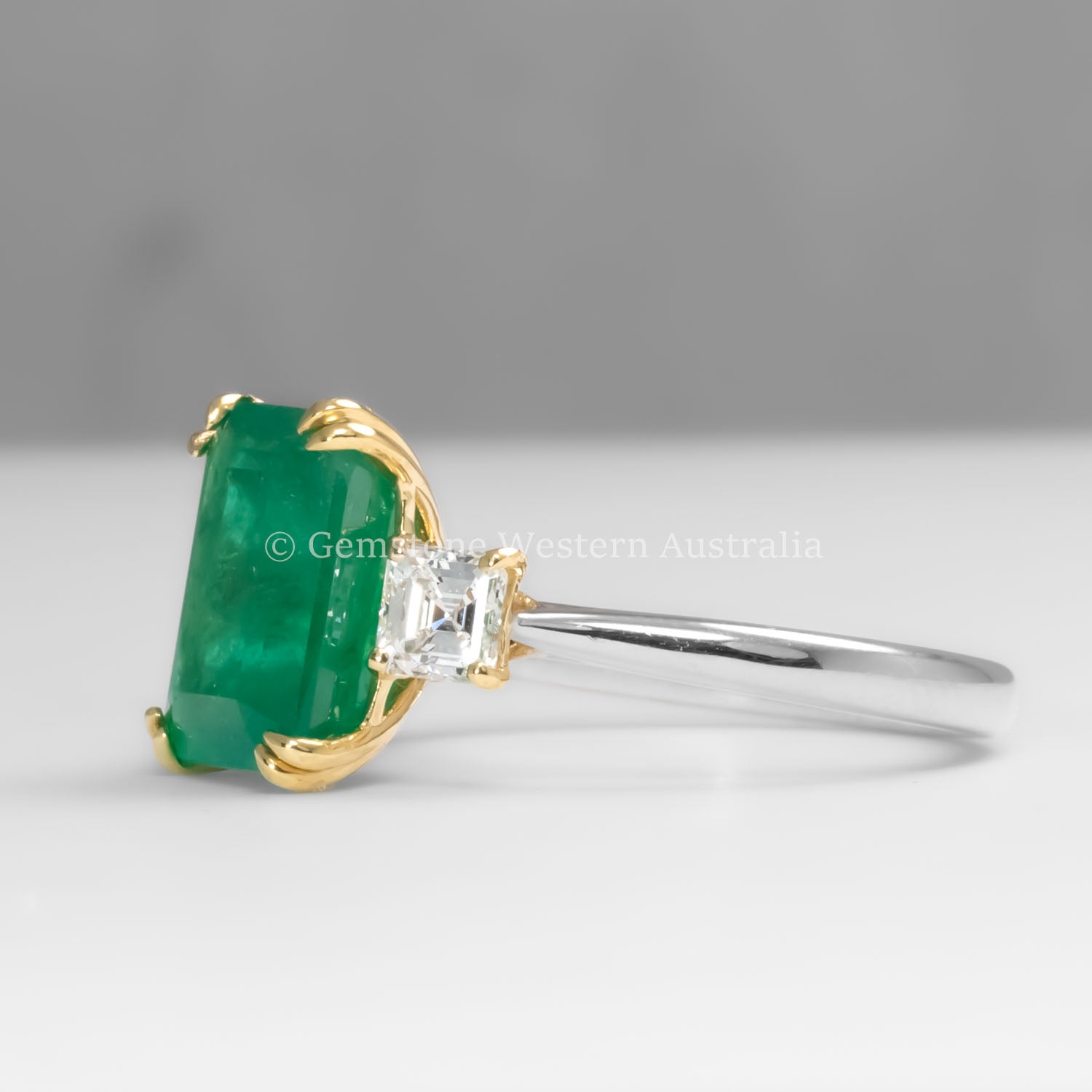 side view of Colombian Emerald and Diamond Ring in 18K Yellow Gold – East West Emerald Cut in neutral background