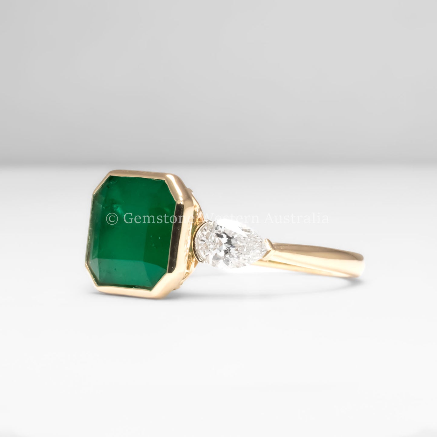 side view of Colombian Emerald and Diamond Ring in 18K Yellow Gold – East West Emerald Cut in white background