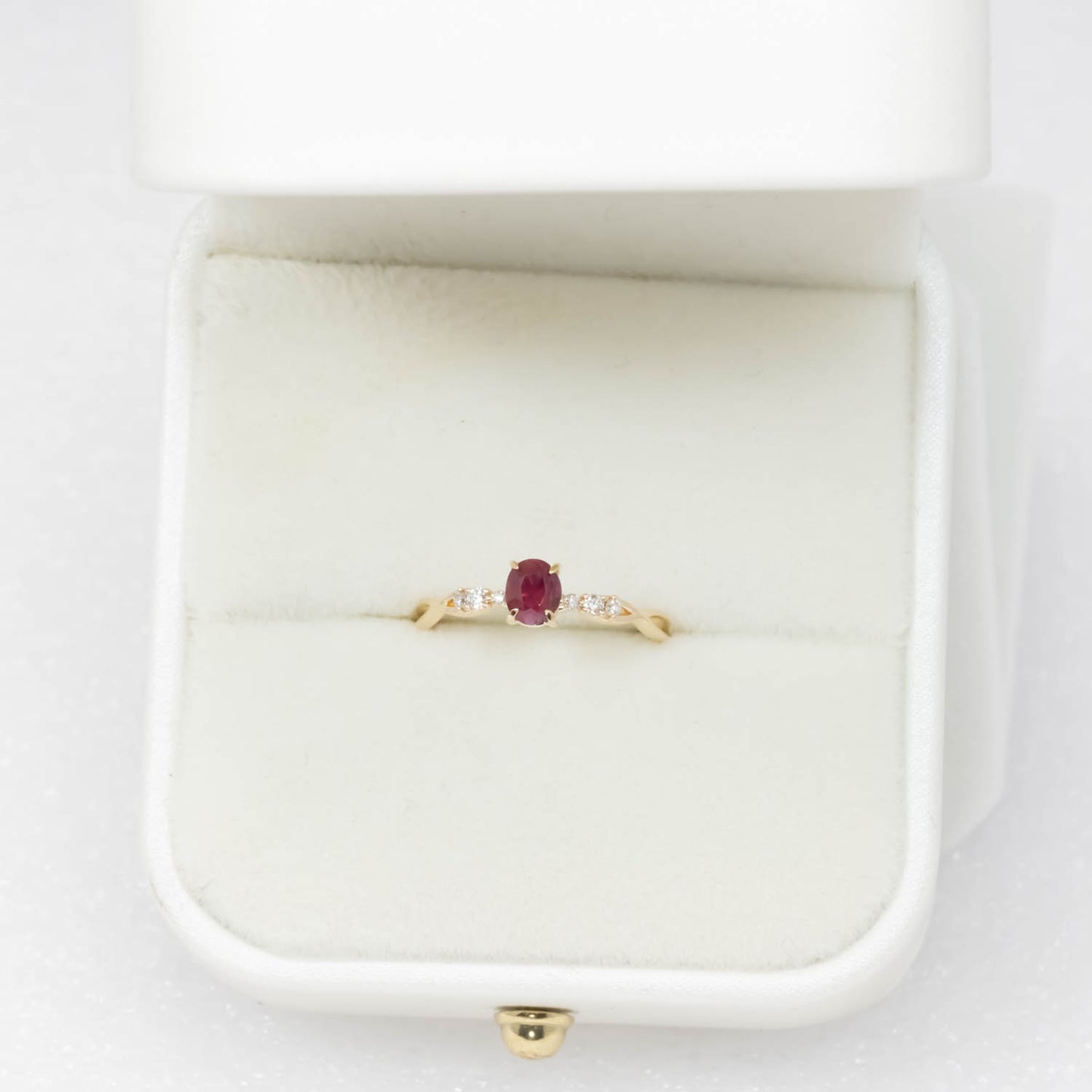front view of a Natural Ruby & Diamond Twisted Band Ring in 18K Yellow Gold in a ring box in neutral background