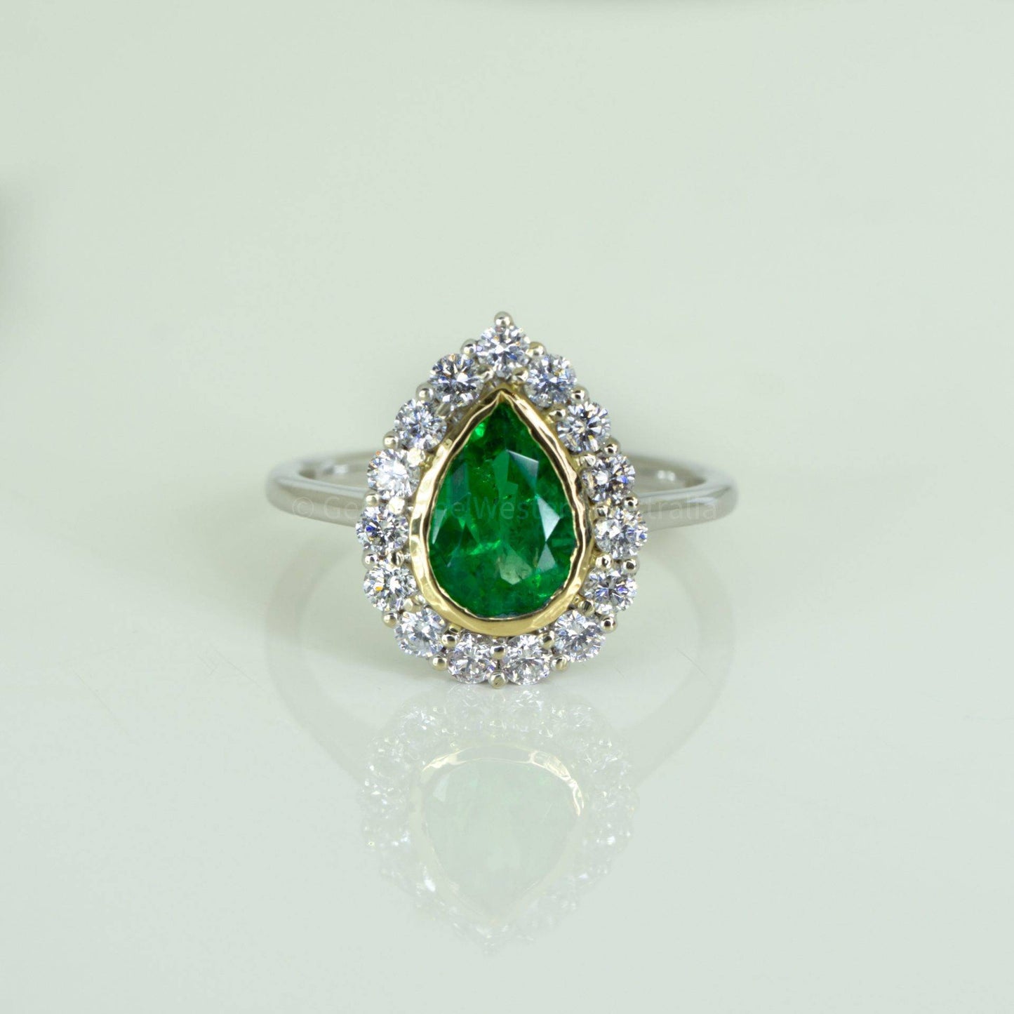 Bezel Set Emerald in a Diamond Halo Ring in 18K Gold
