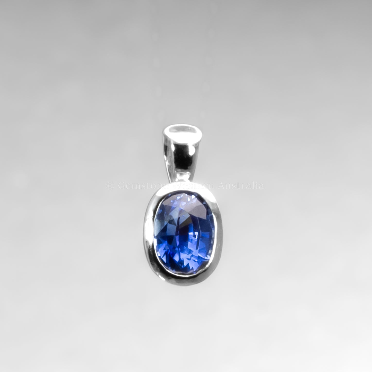 platinum pendant with a blue gemstone on a gray background