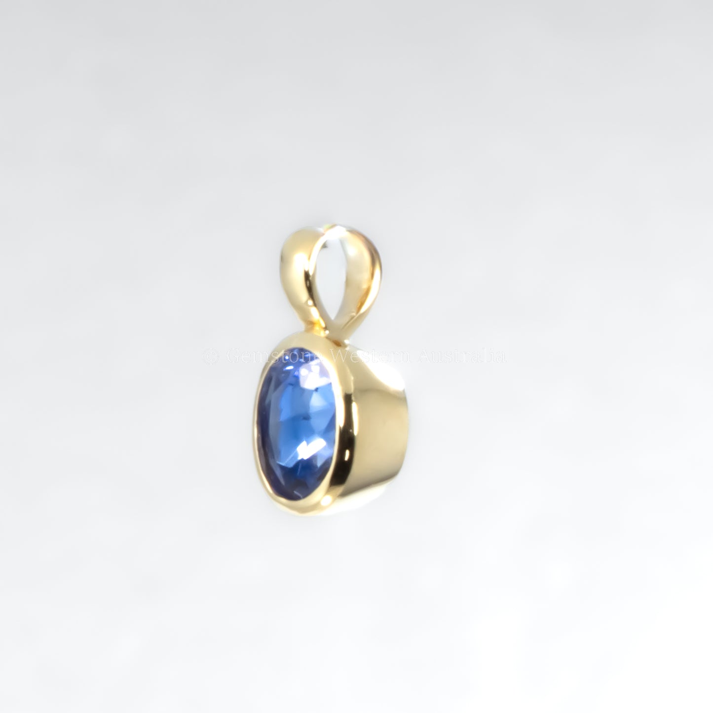 Gold pendant with a blue gemstone on a light gray background