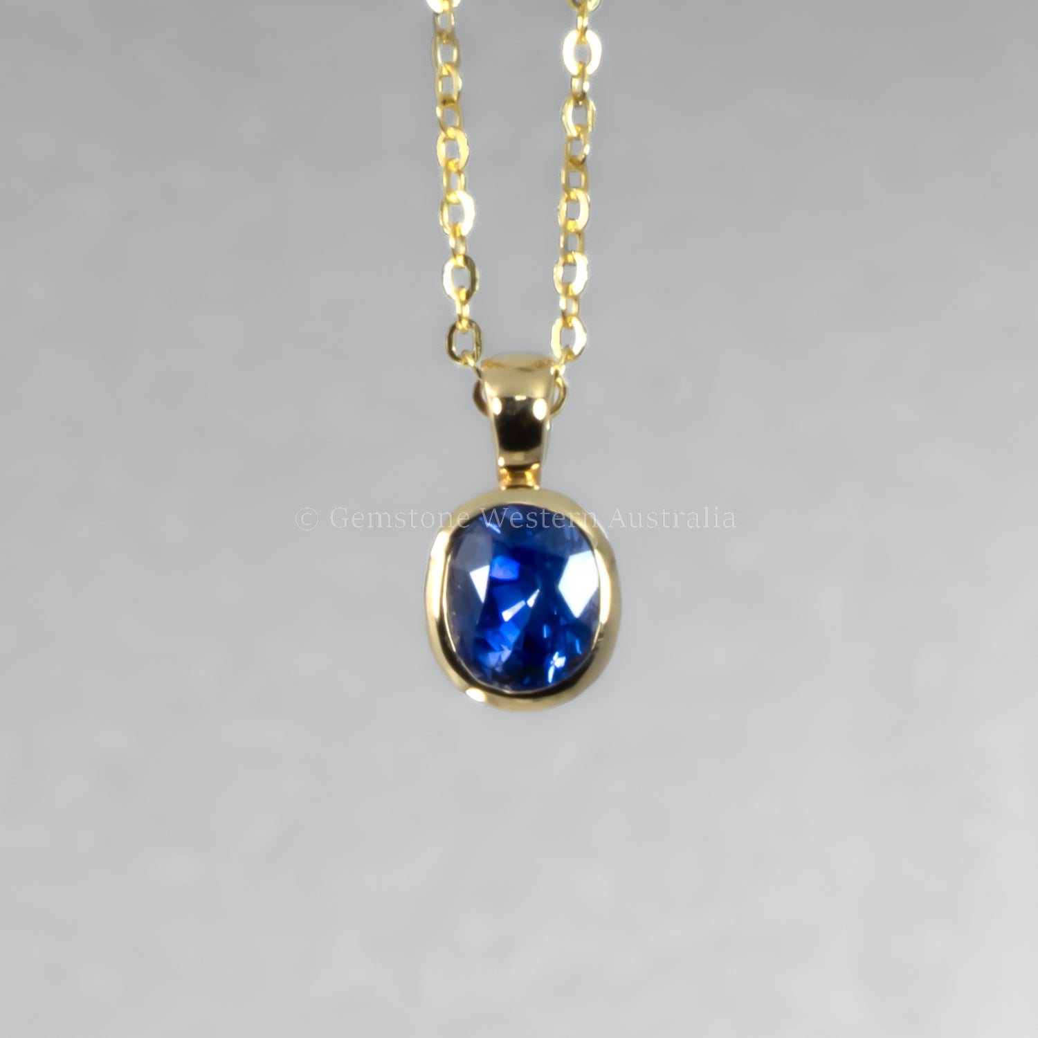Gold necklace with a blue gemstone pendant on a gray background
