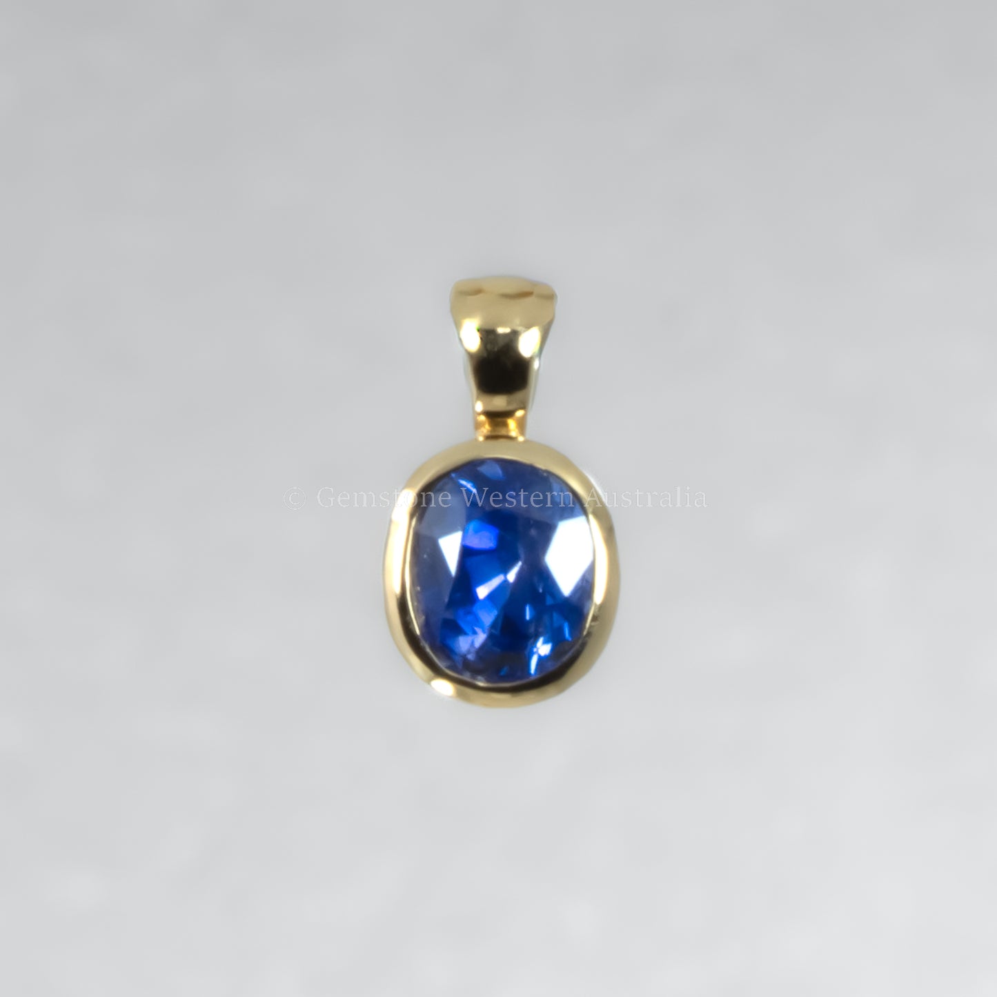 Gold pendant with a blue gemstone on a gray background