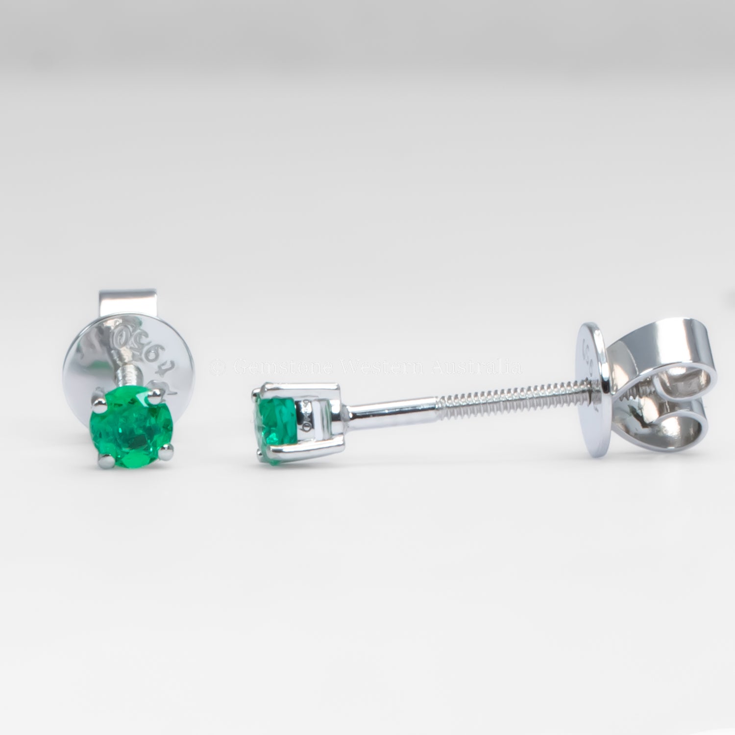 contrast of front and side view of platinum stud earrings with emerald gemstones on a white background
