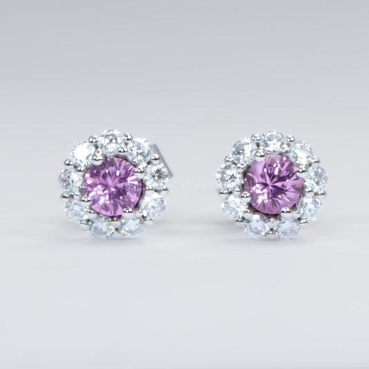 Pair of earrings with pink sapphires and diamond-like stones on a light gray background