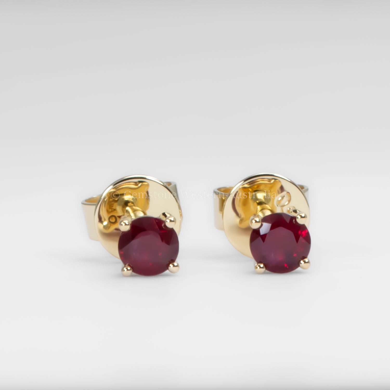 Gold earrings with ruby gemstones on a white background