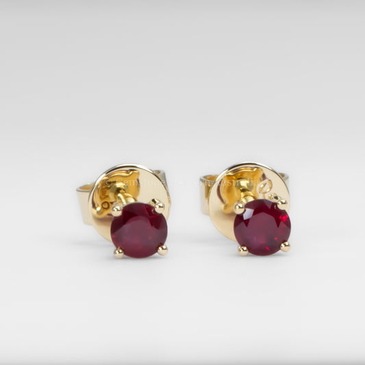 Gold earrings with ruby gemstones on a white background