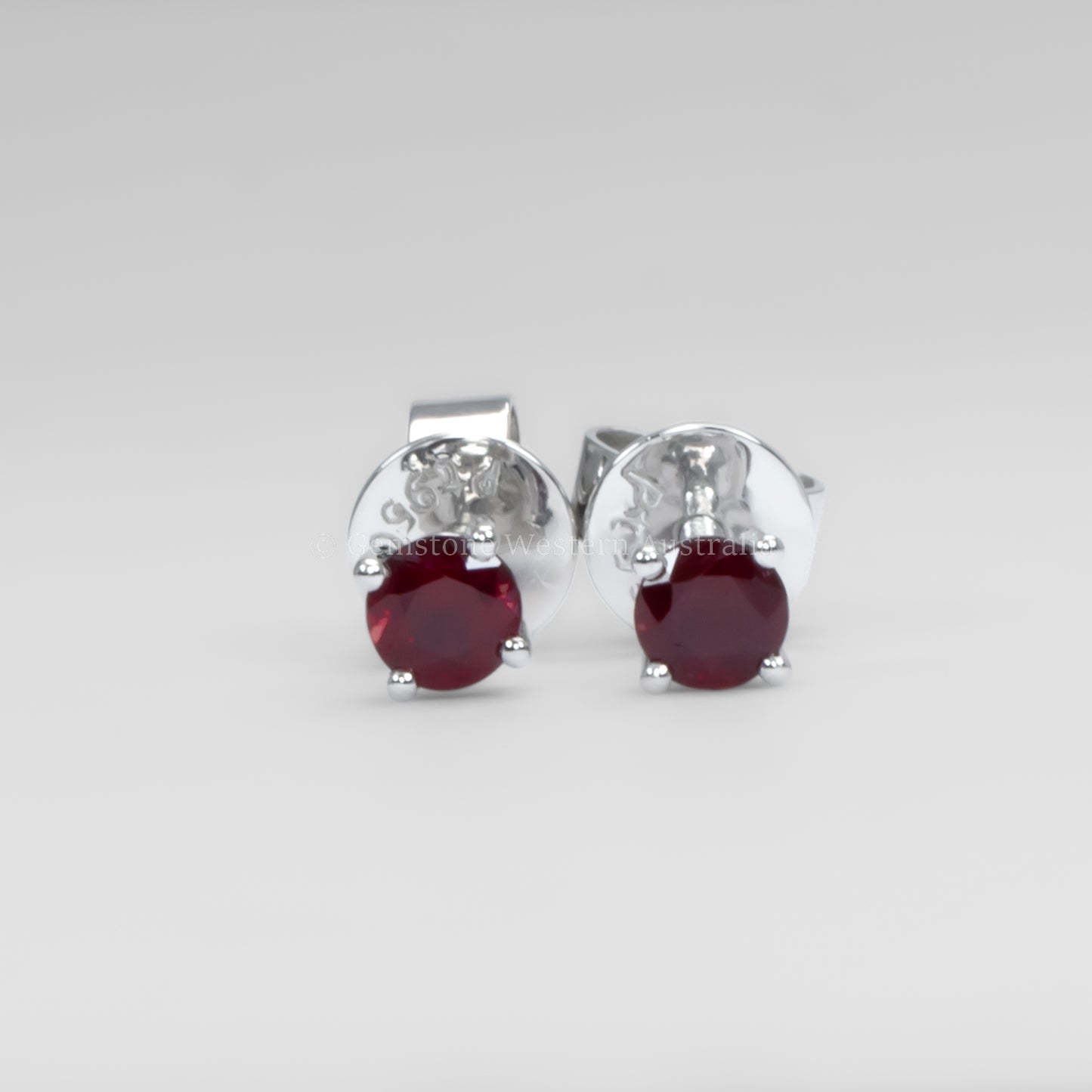 Ruby earrings in platinum on a gray background