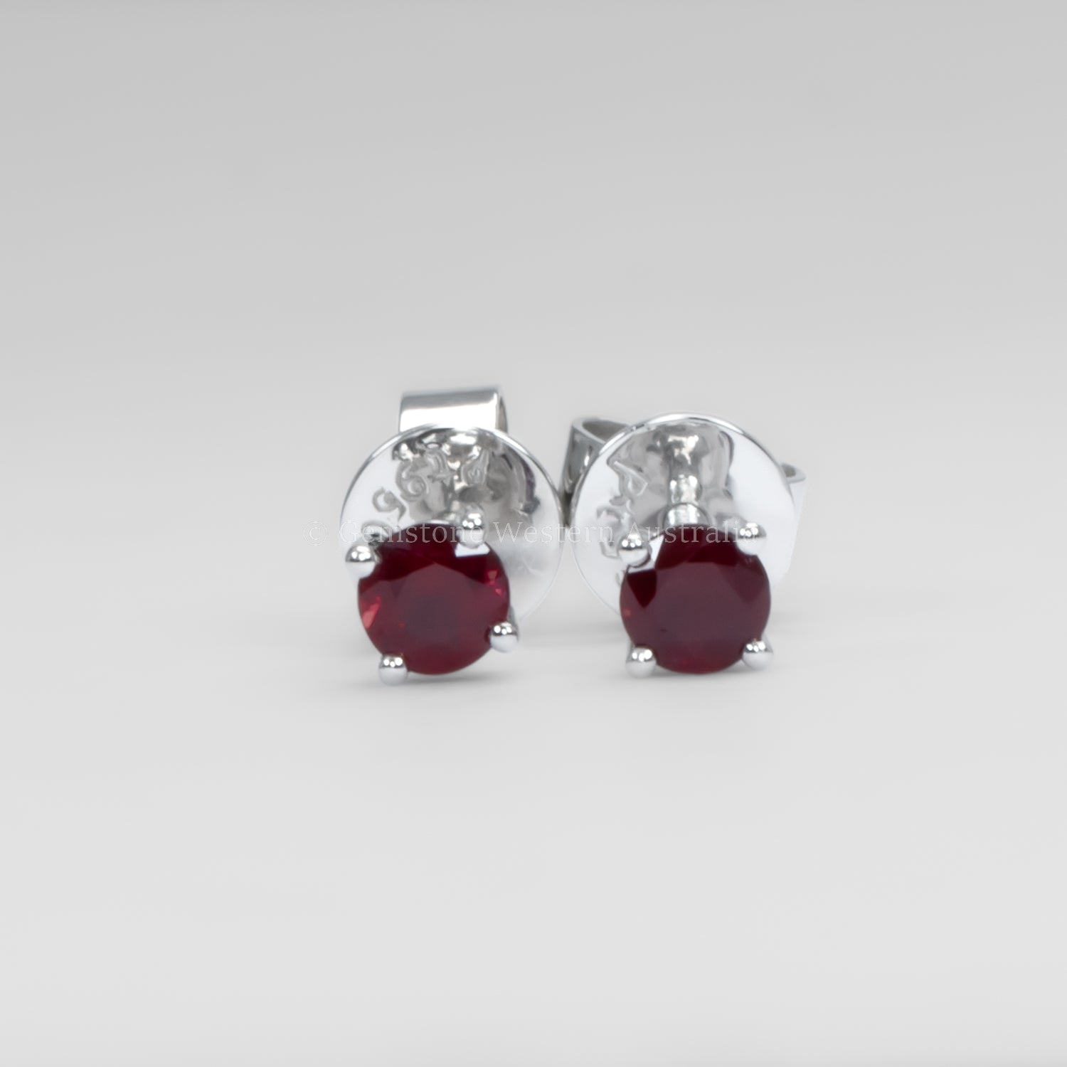 Ruby earrings in platinum on a gray background