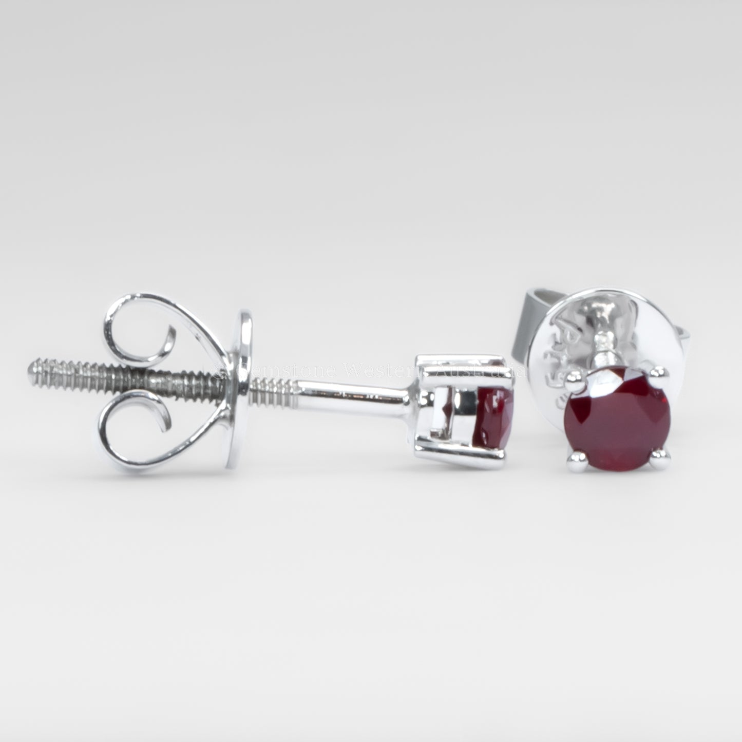 contrast of side and front view of ruby earrings in platinum on a gray background