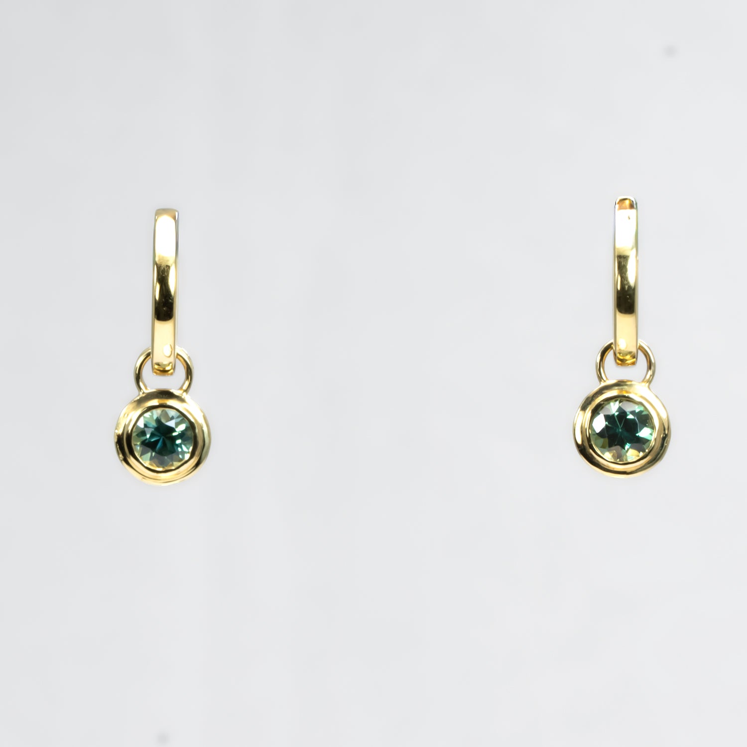 Australian sapphires dangling earrings in 18K gold in a white background