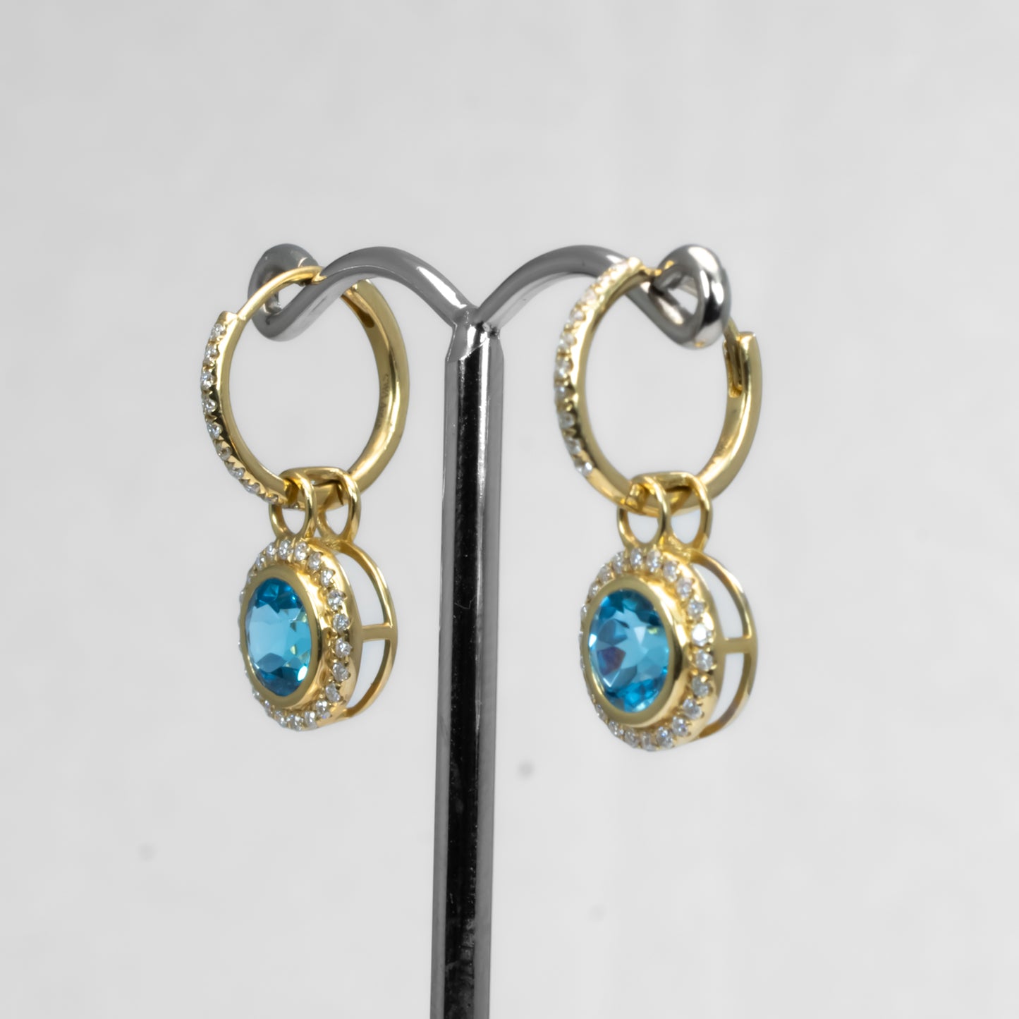 side view o Yellow gold Swiss blue topaz earrings in white background