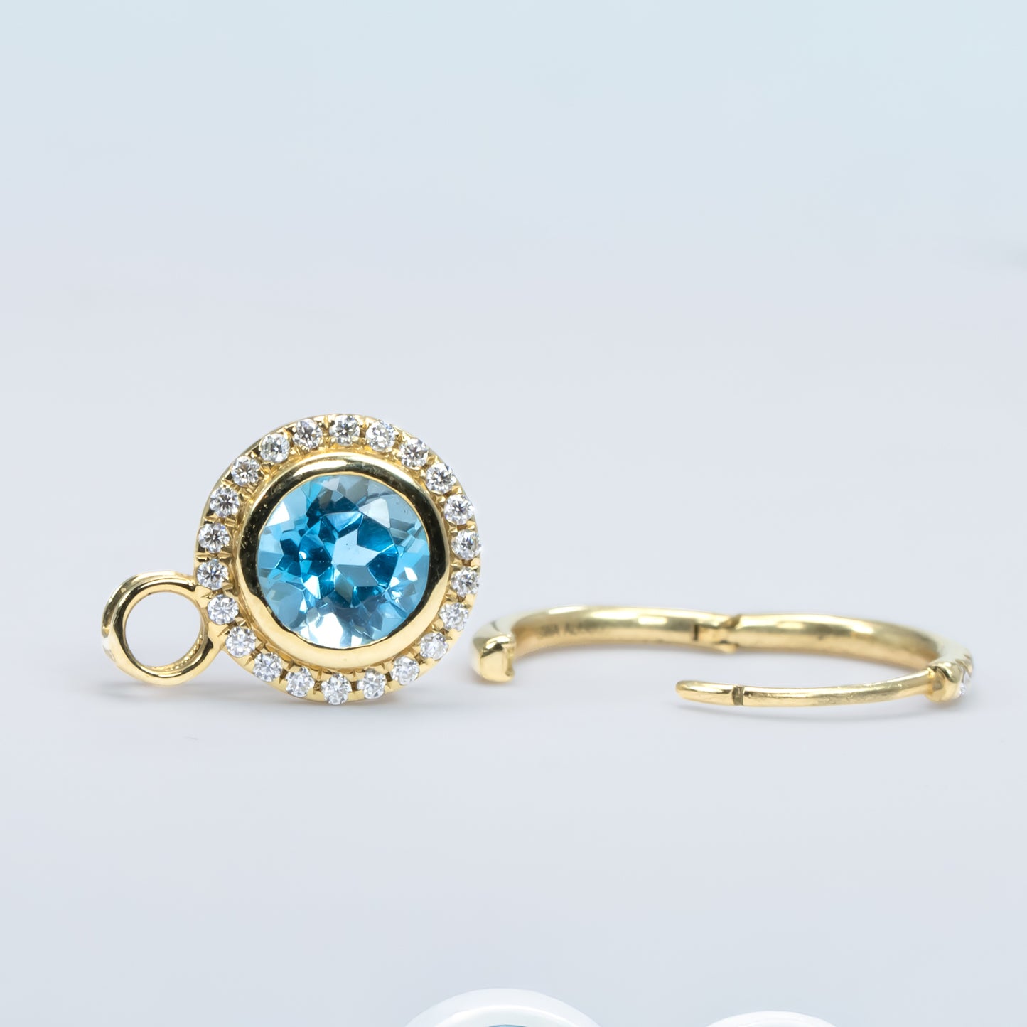 photo of Swiss blue topaz charm and gold hoop on white background