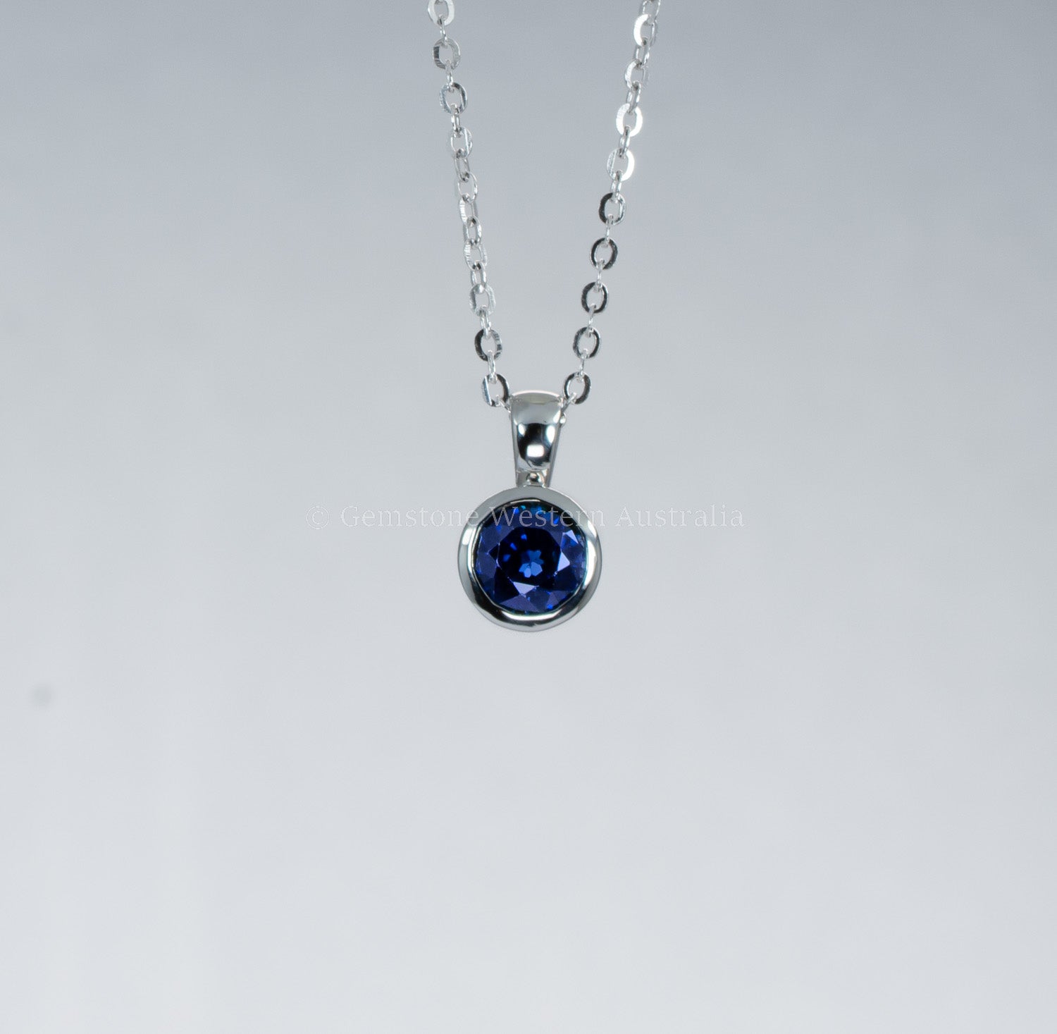 Silver necklace with a blue gemstone pendant on a gray background