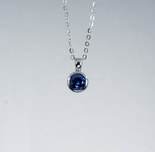 Silver necklace with a blue gemstone pendant on a gray background