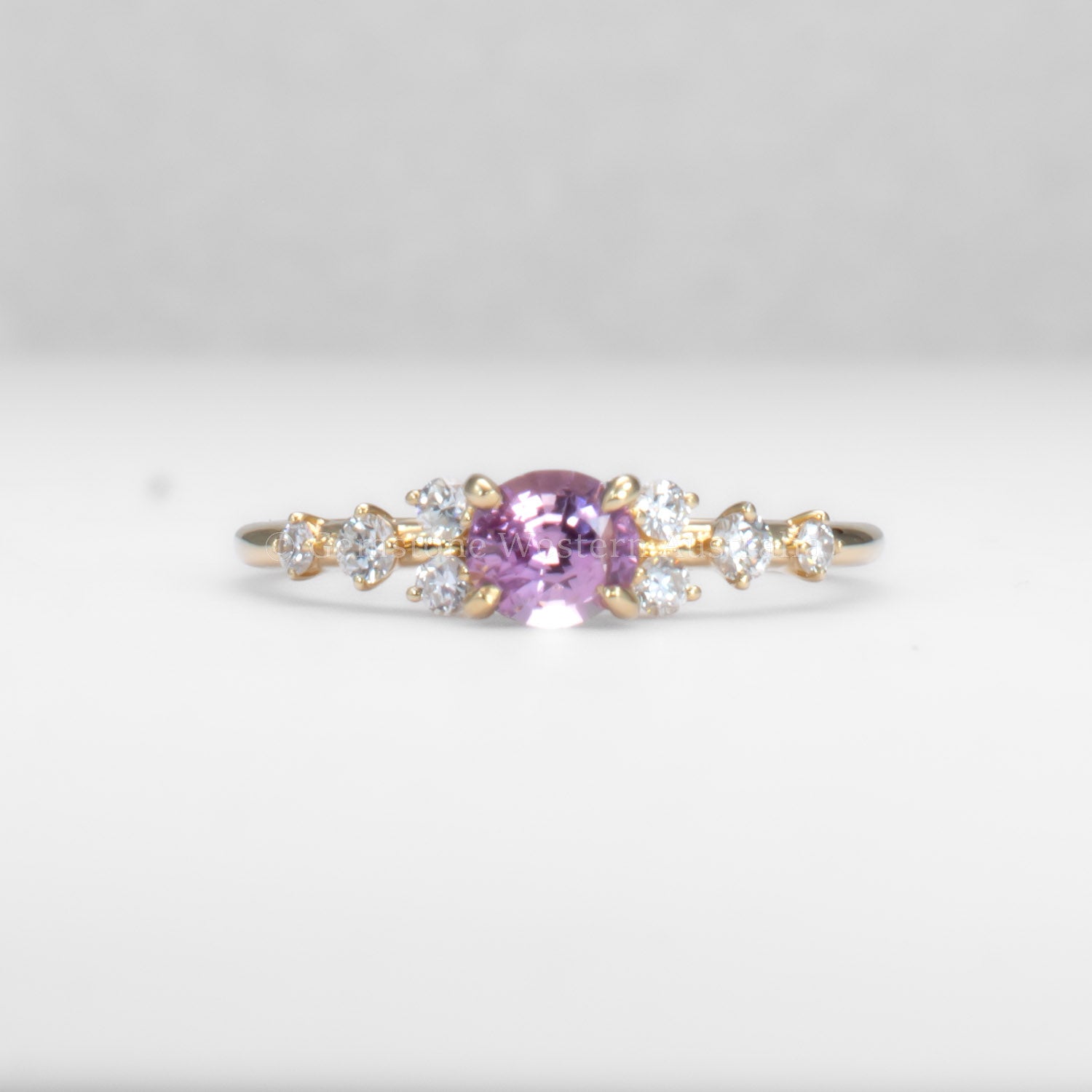 Gold ring with natural pink sapphire and diamonds on a gray background