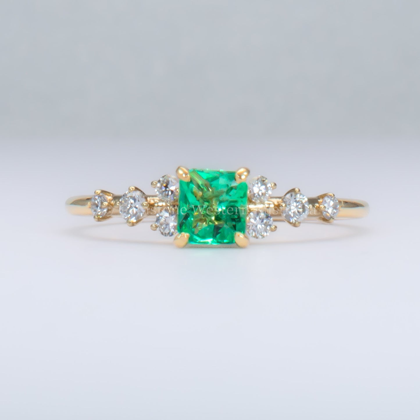 Yellow gold ring with Colombian emerald and diamonds on gray background