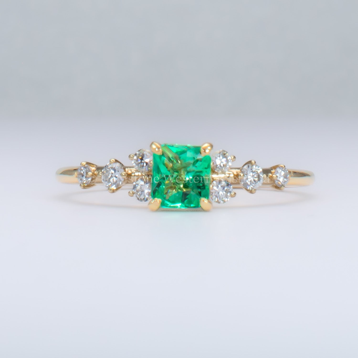 Yellow gold ring with Colombian emerald and diamonds on gray background