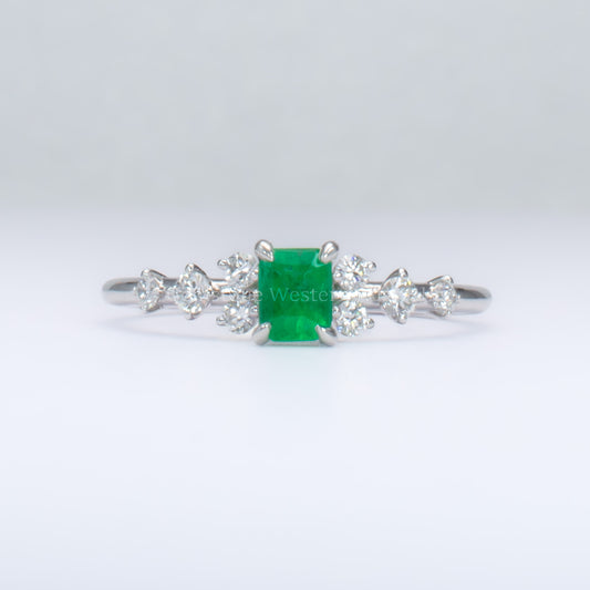 platinum ring with emerald and diamonds in gray background