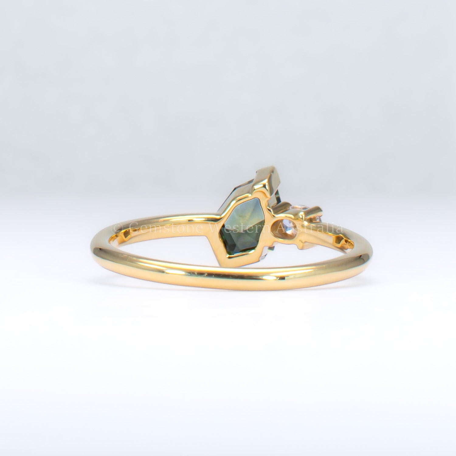 back view of toi et moi teal sapphire gold ring in gray background