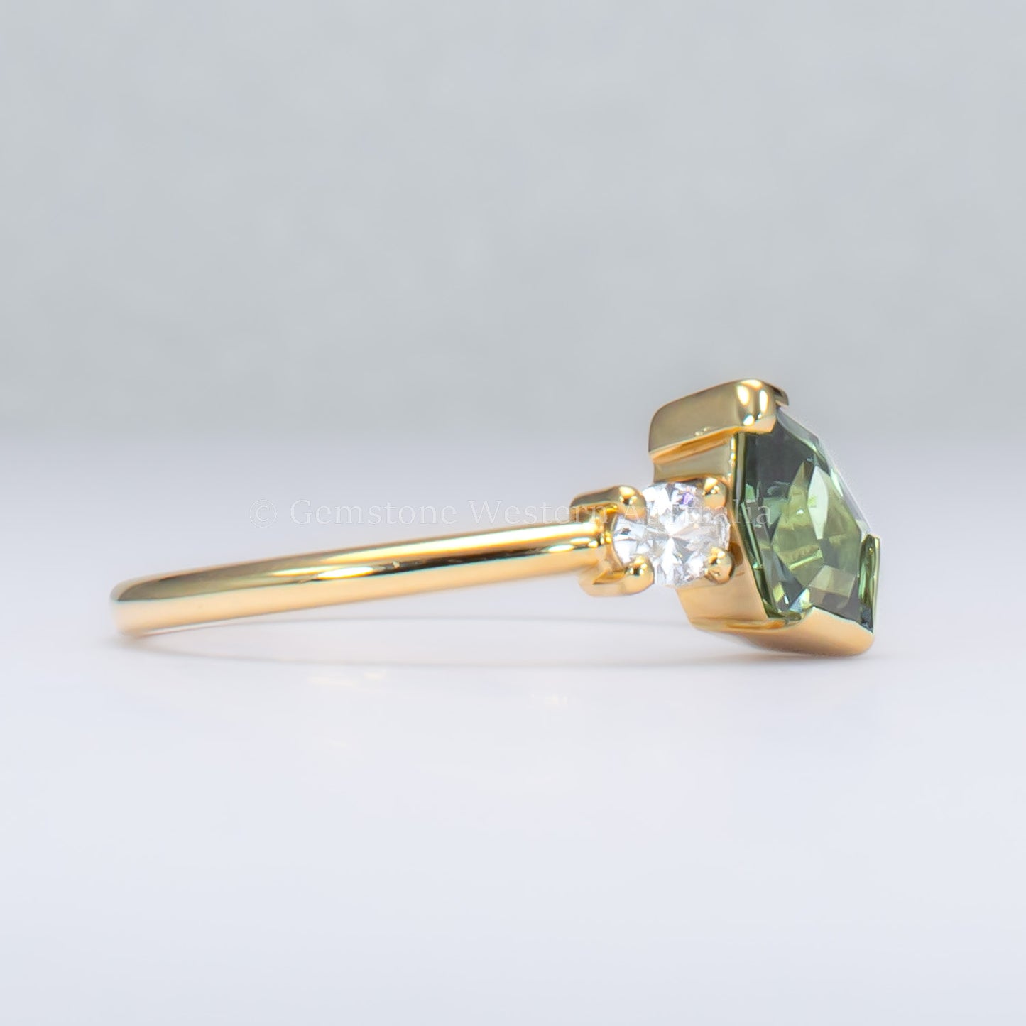 side view of toi et moi teal sapphire gold ring in gray background