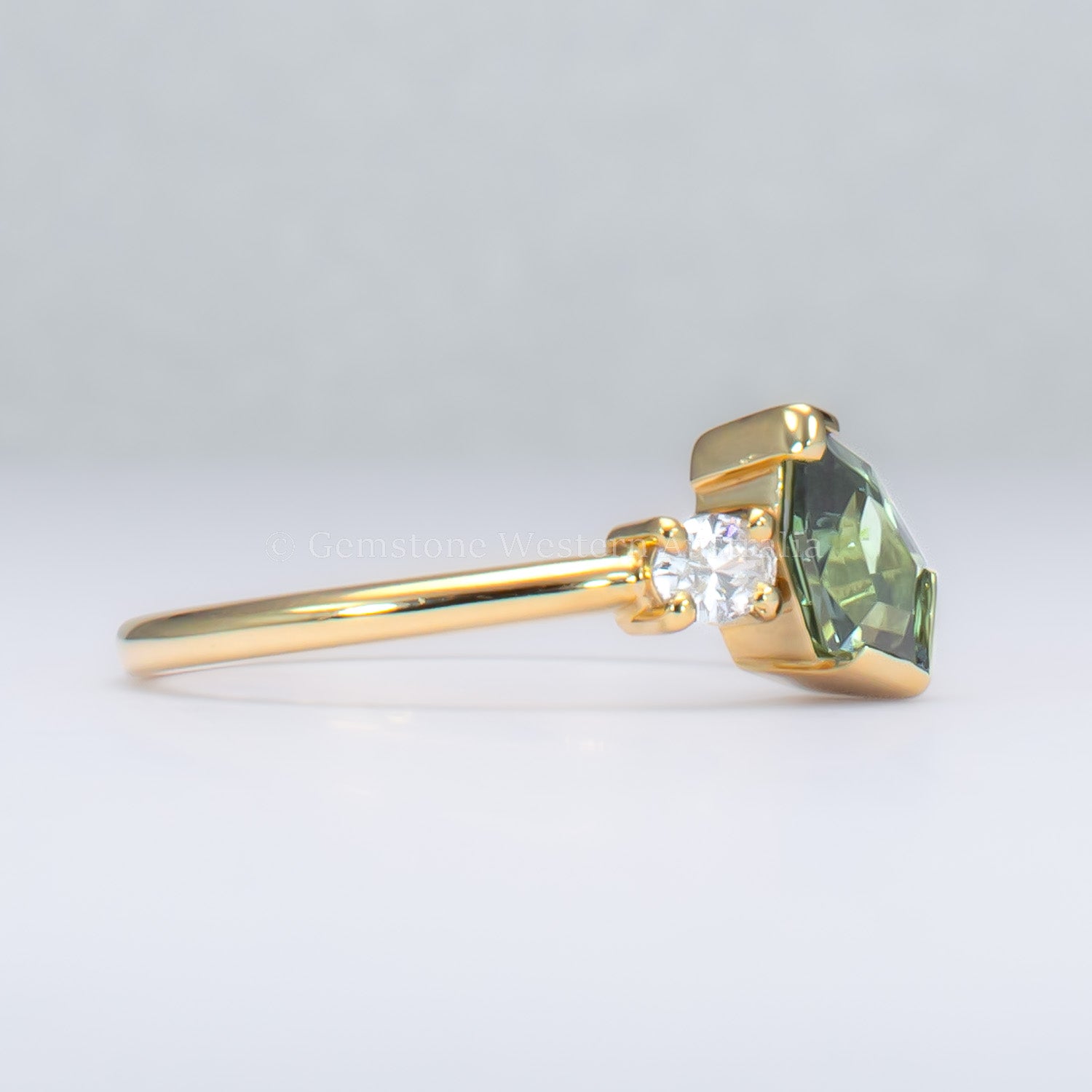 side view of toi et moi teal sapphire gold ring in gray background