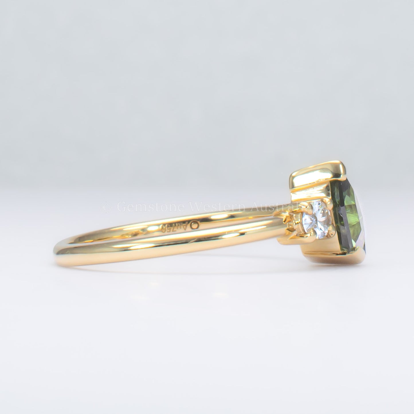 side profile of toi et moi teal sapphire gold ring in gray background