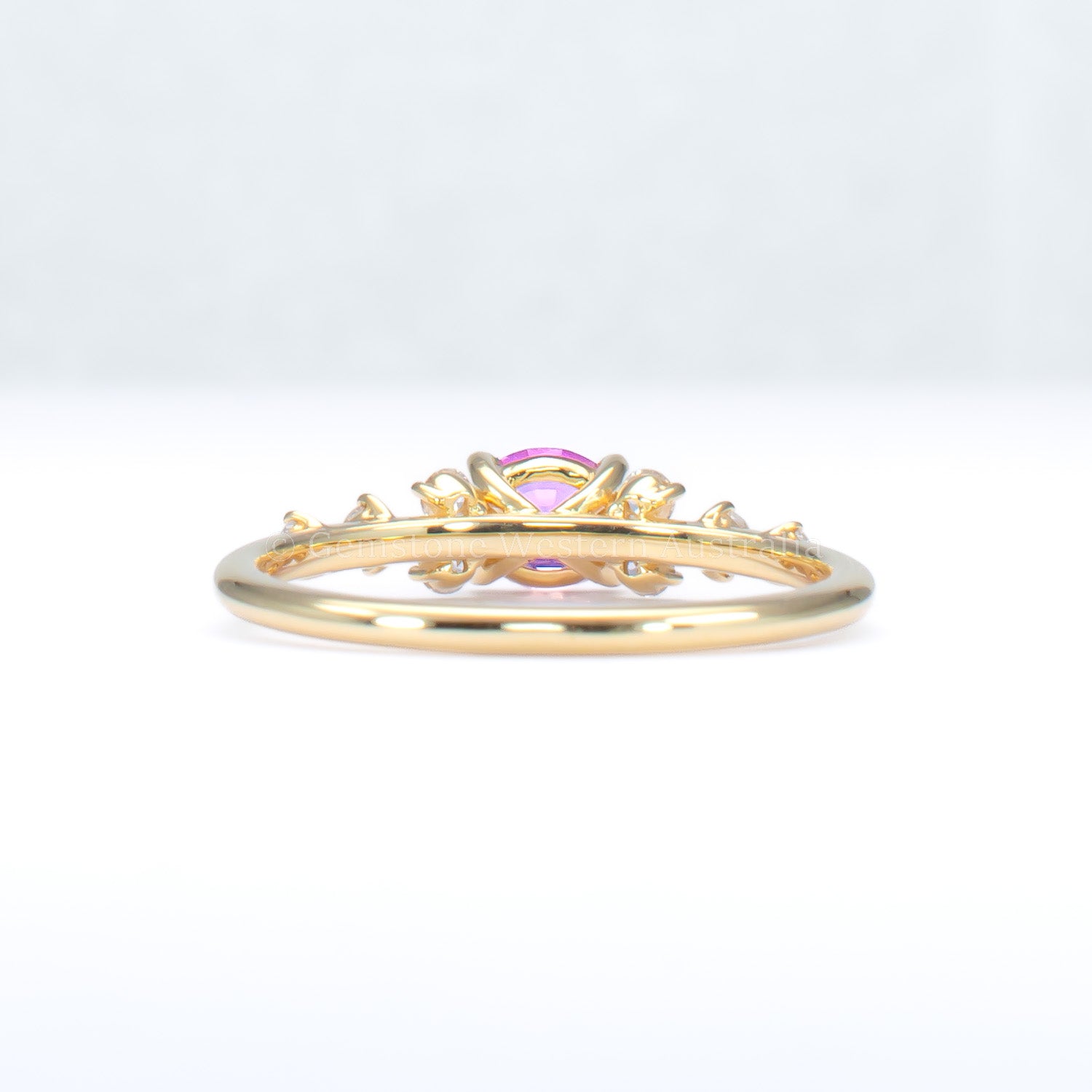 back view of gold ring with natural pink sapphire and diamonds on a gray background