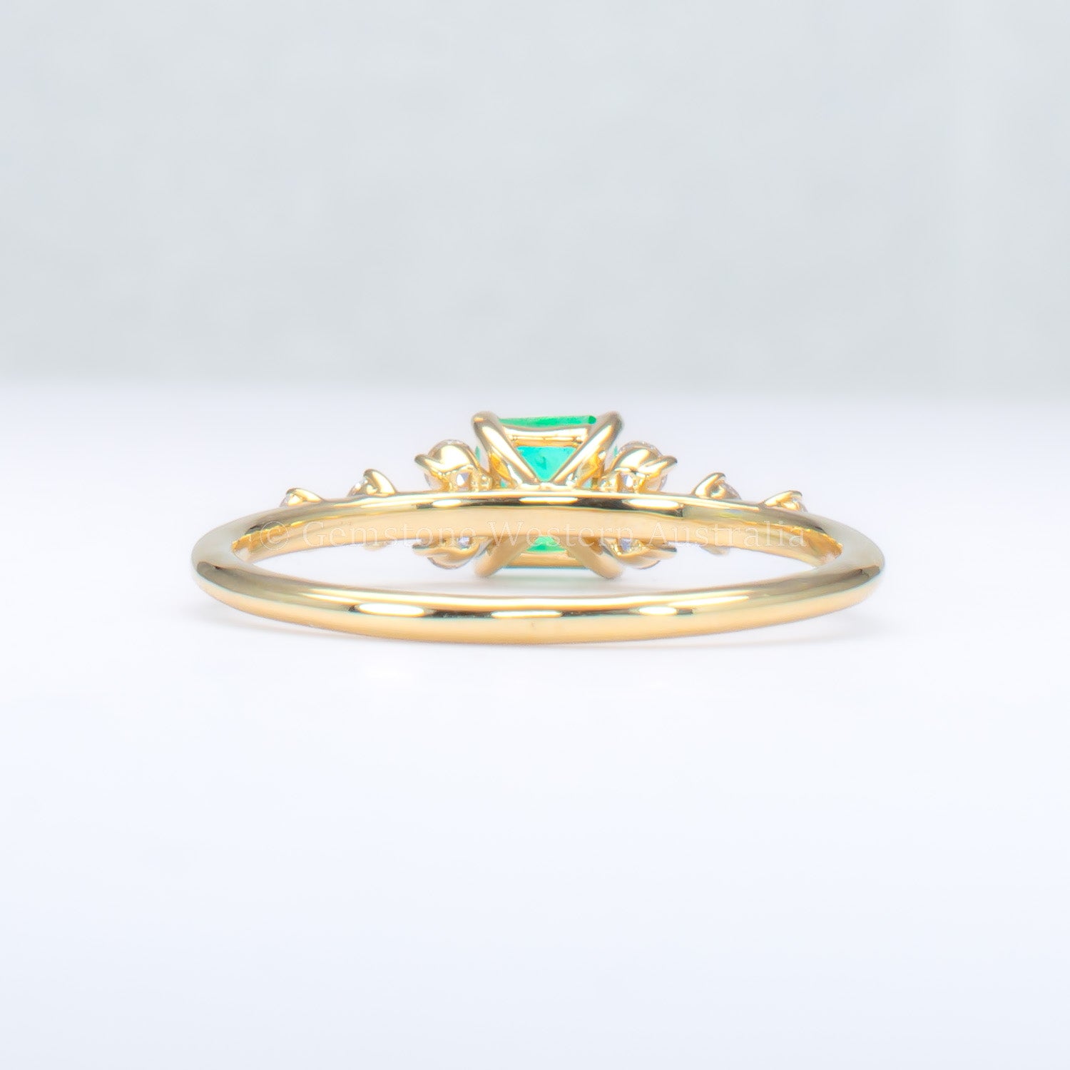 back view of Yellow gold ring with Colombian emerald and diamonds on gray background