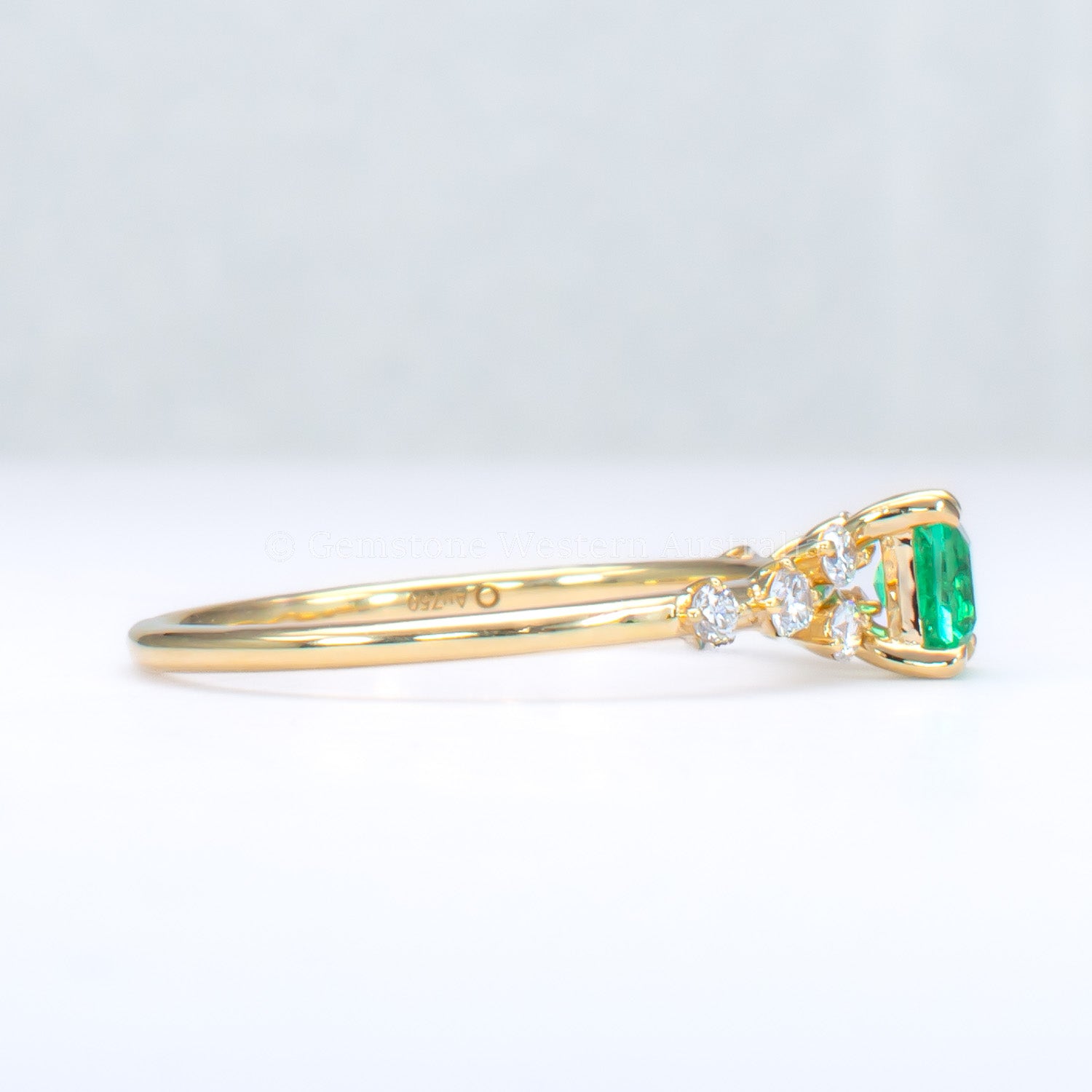 side view of Yellow gold ring with Colombian emerald and diamonds on gray background