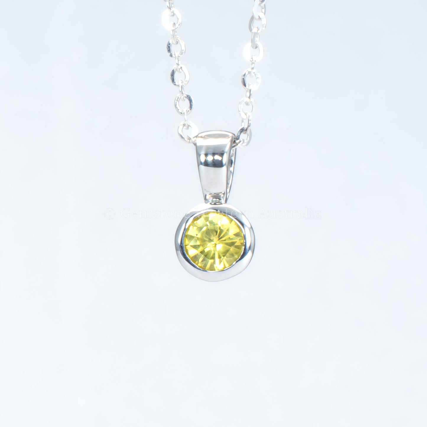 platinum pendant with yellow sapphire in a gray background
