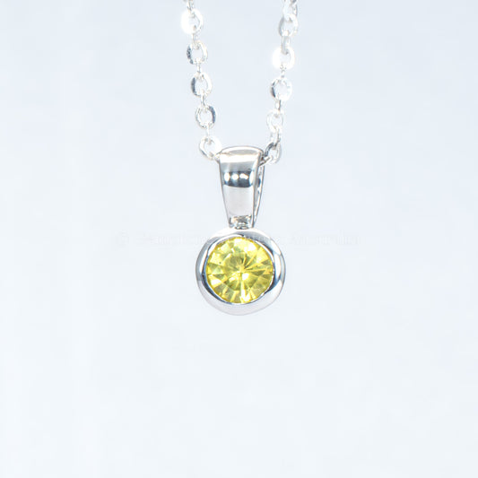platinum pendant with yellow sapphire in a gray background