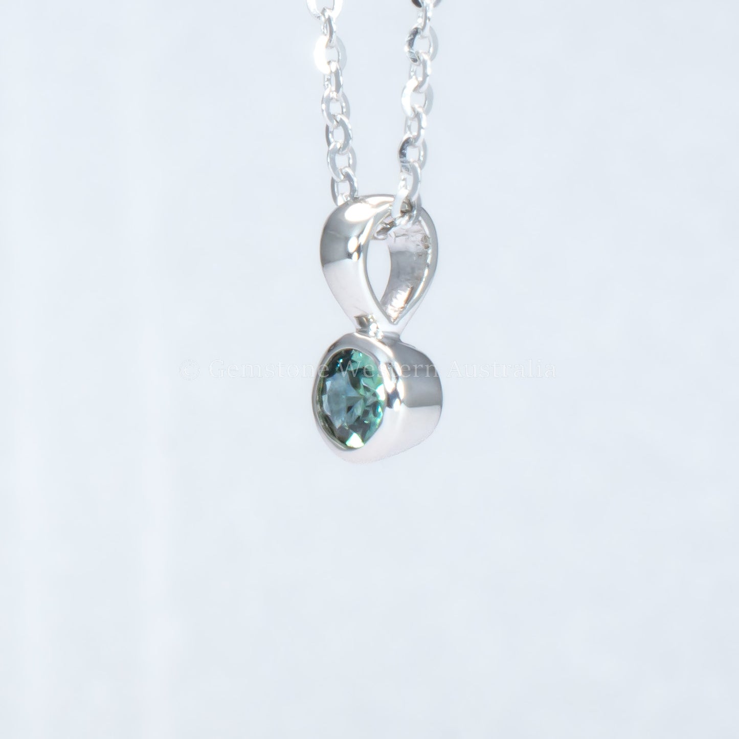 side view of Australian teal sapphire platinum pendant in gray background