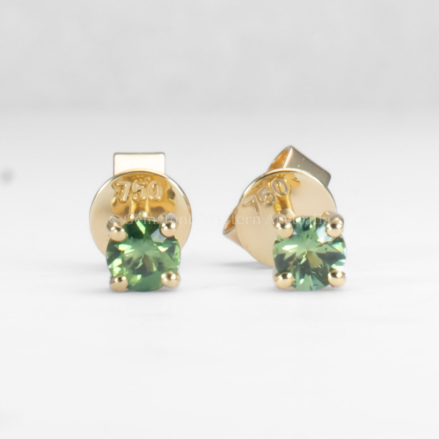 teal sapphire earrings in gold in gray background