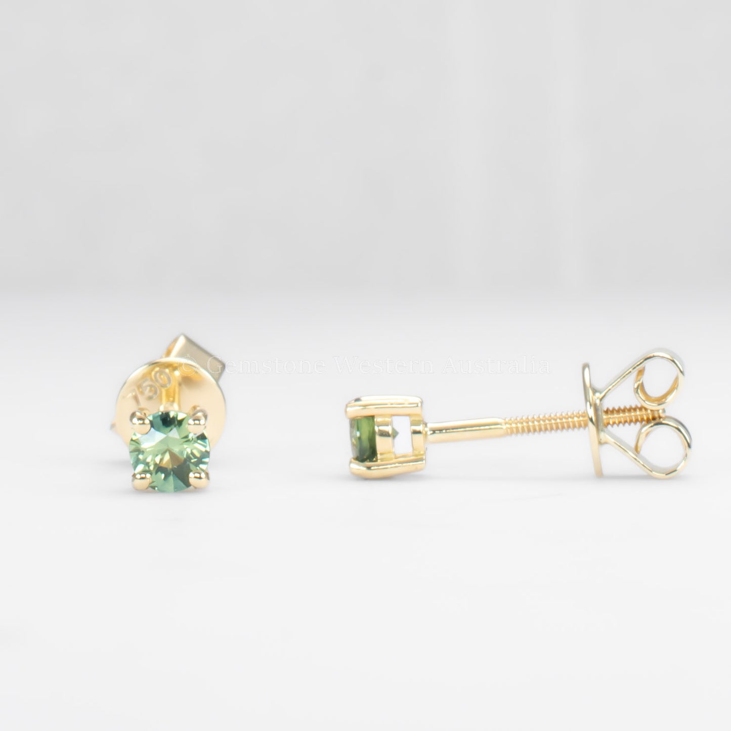 front and side teal sapphire earrings in gold in gray background