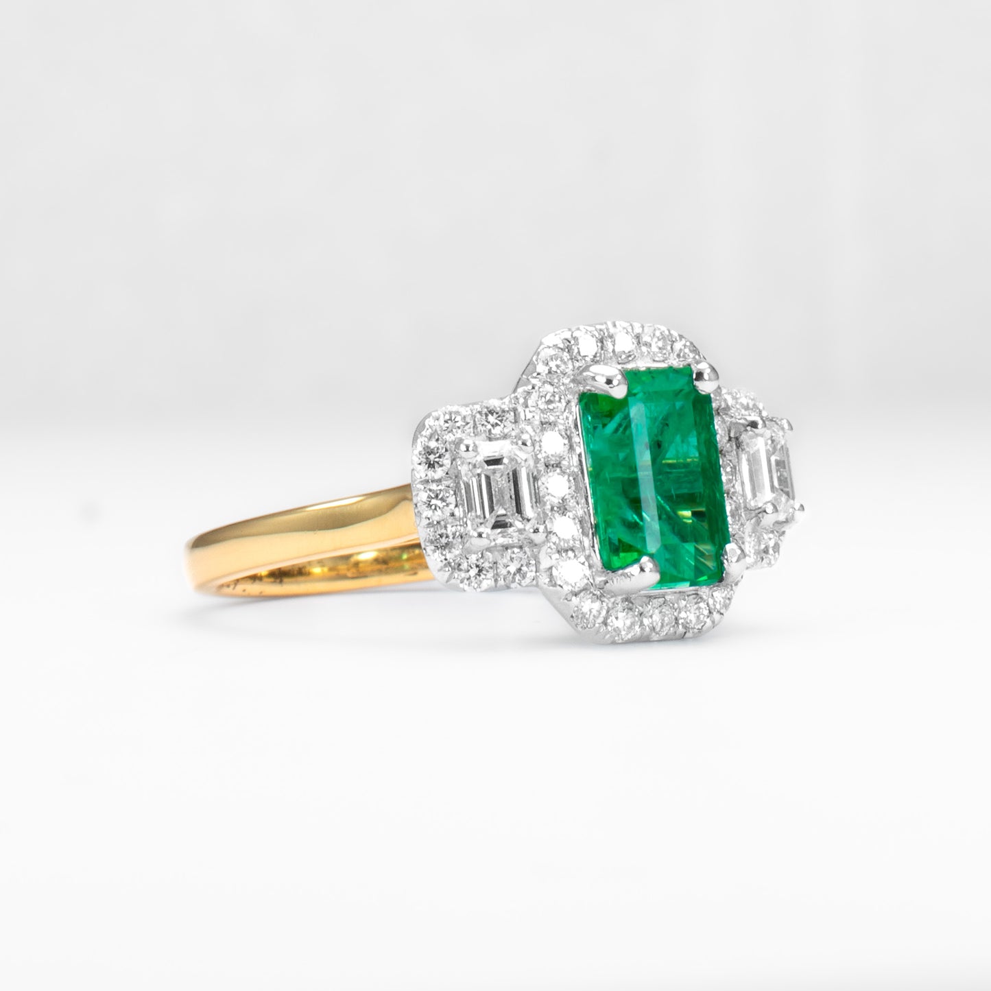 Elongated Colombian Emerald Three-Stone Halo Ring in Platinum and Gold