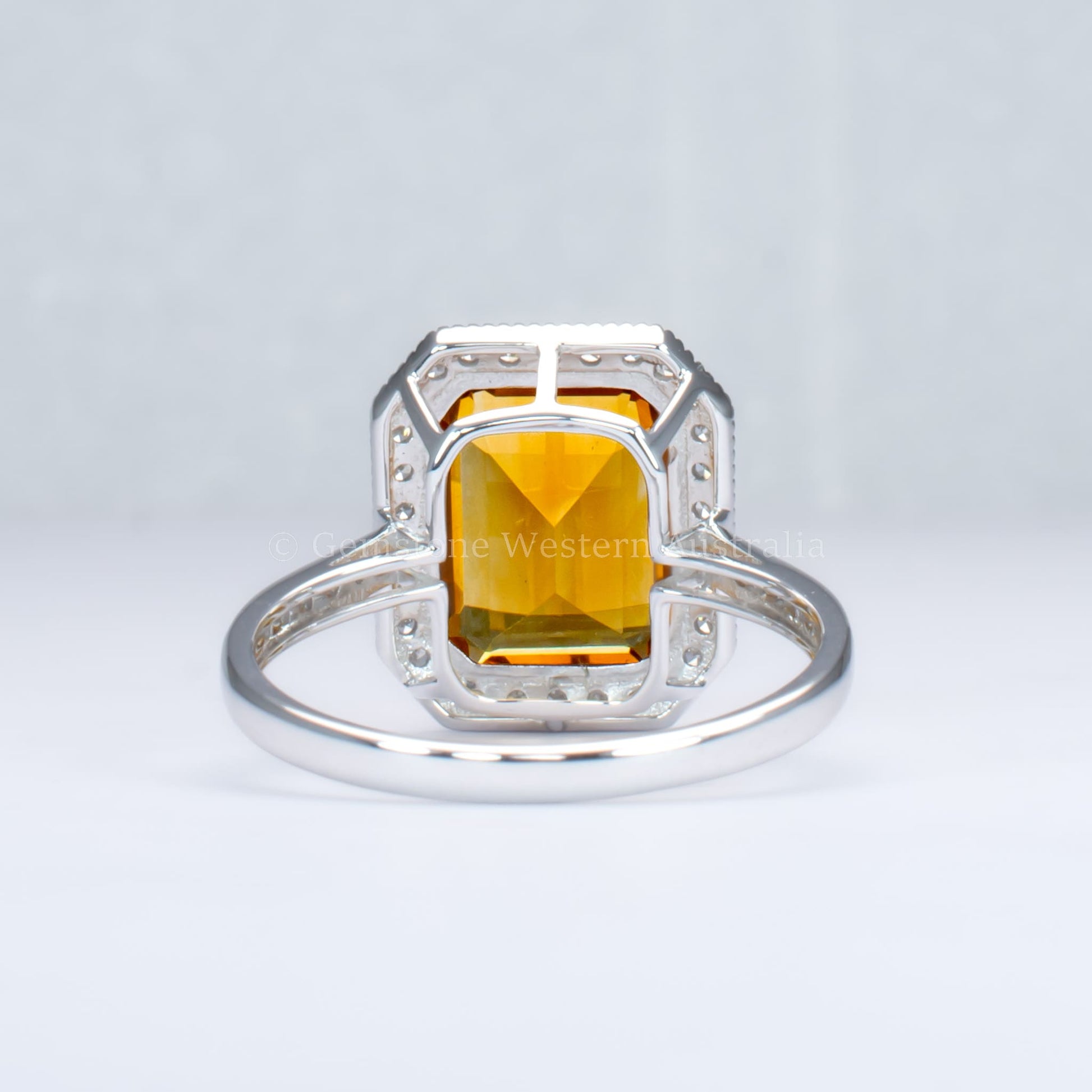back view of Citrine and diamond halo ring in 18K white gold in light gray background