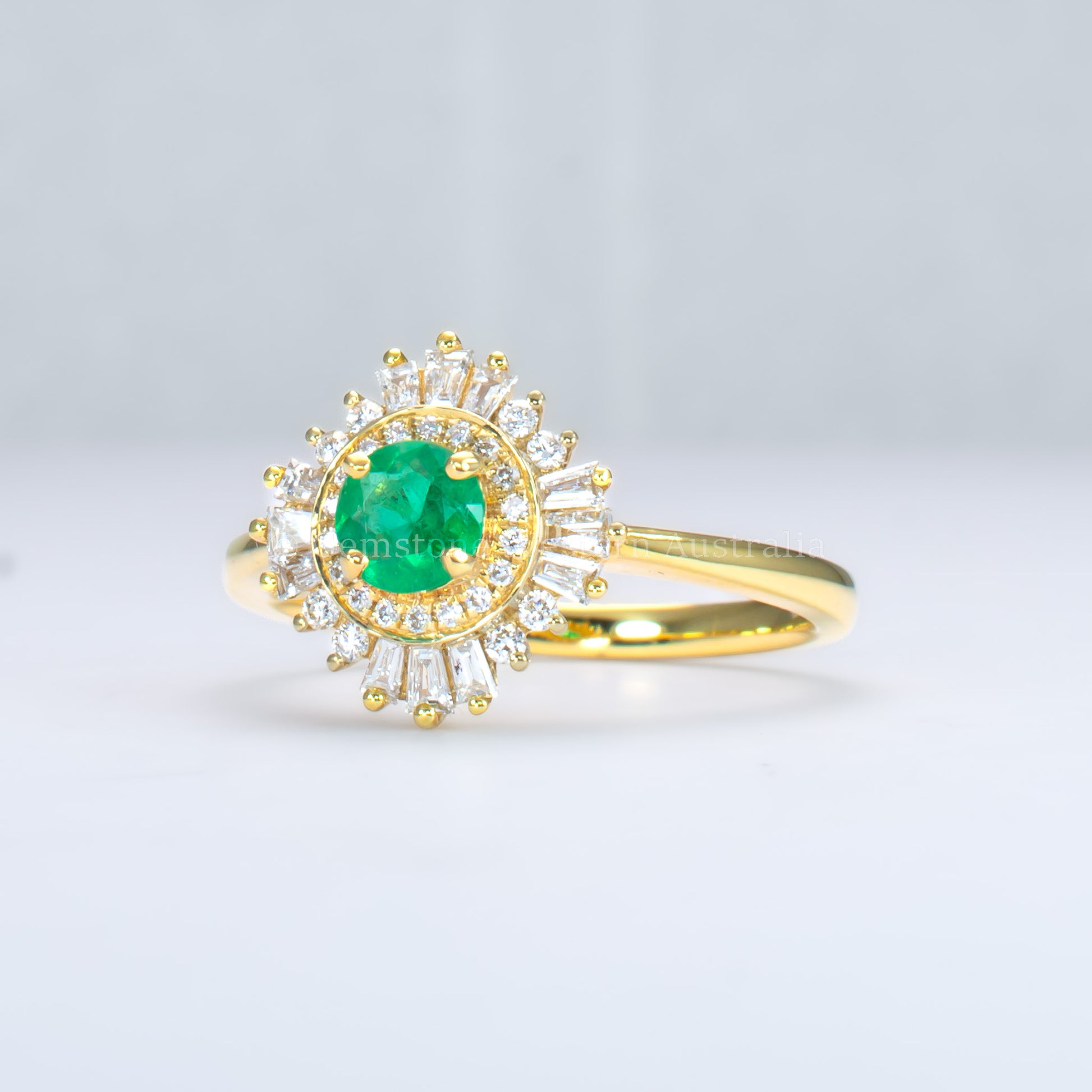 side view of emerald Art Deco ring with diamond halo in light gray background
