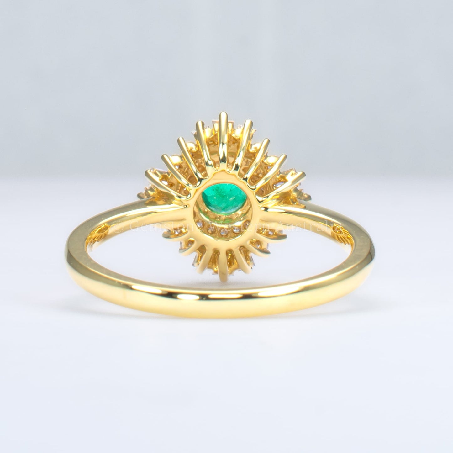 back view of emerald Art Deco ring with diamond halo in light gray background