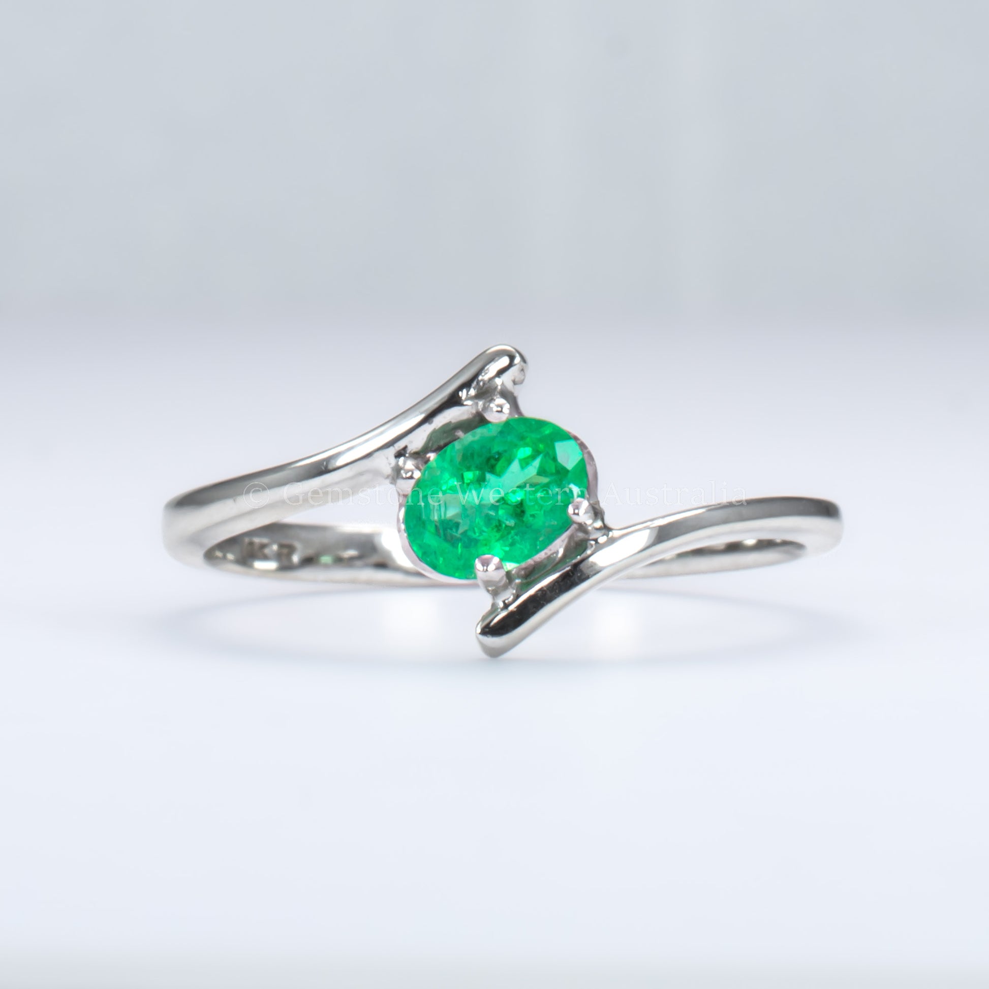 white gold ring with natural Colombian emerald in light gray background