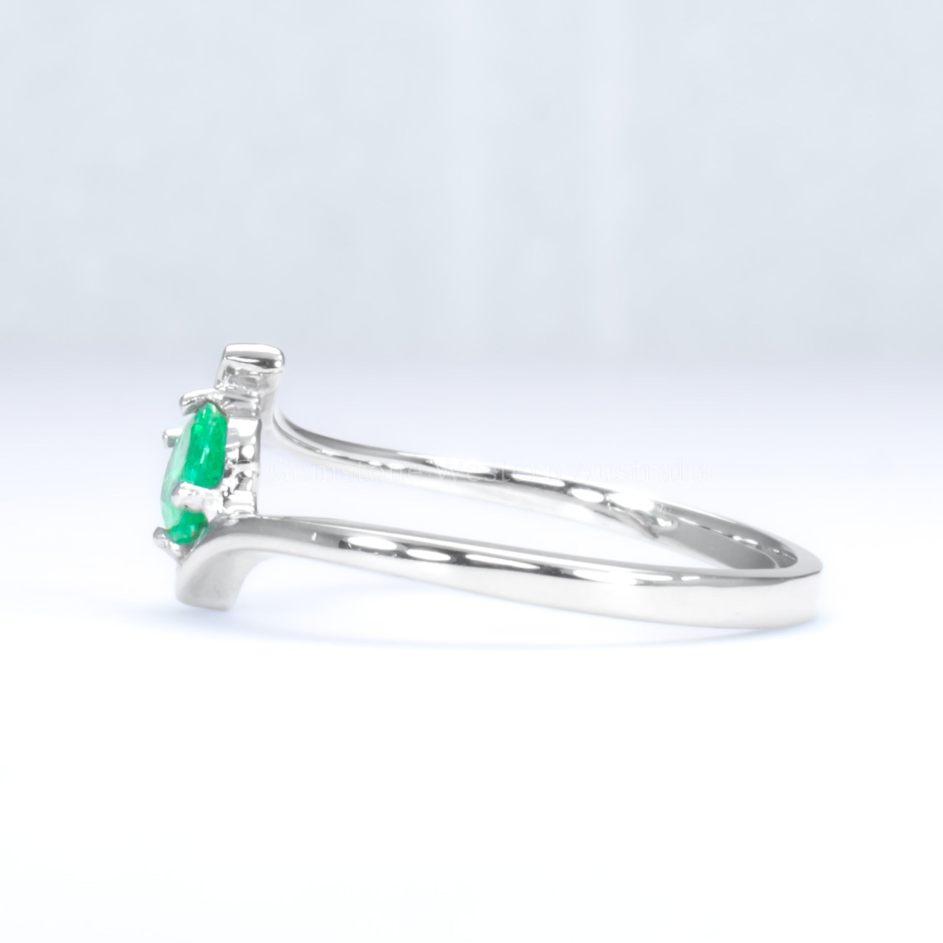 side view of white gold ring with natural Colombian emerald in light gray background