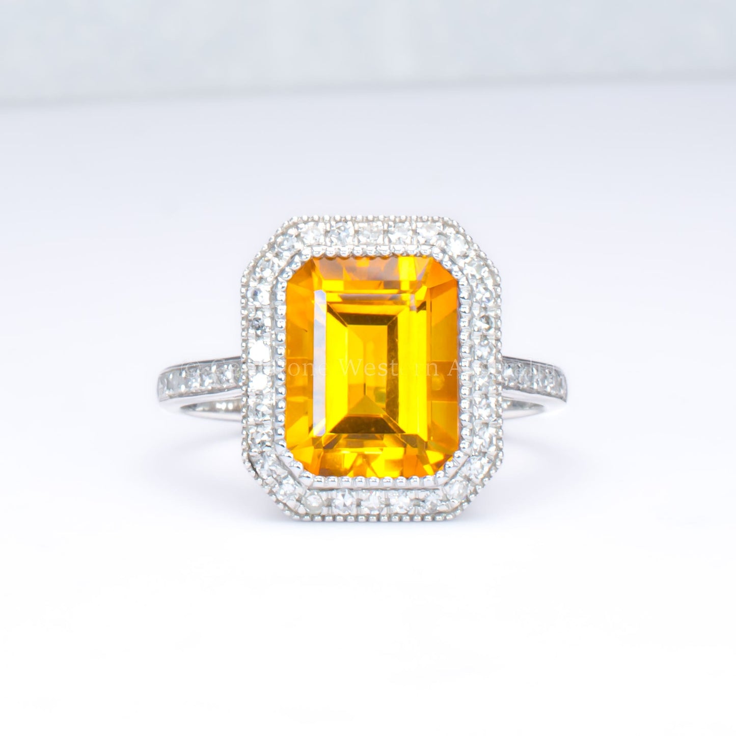 Citrine and diamond halo ring in 18K white gold in light gray background