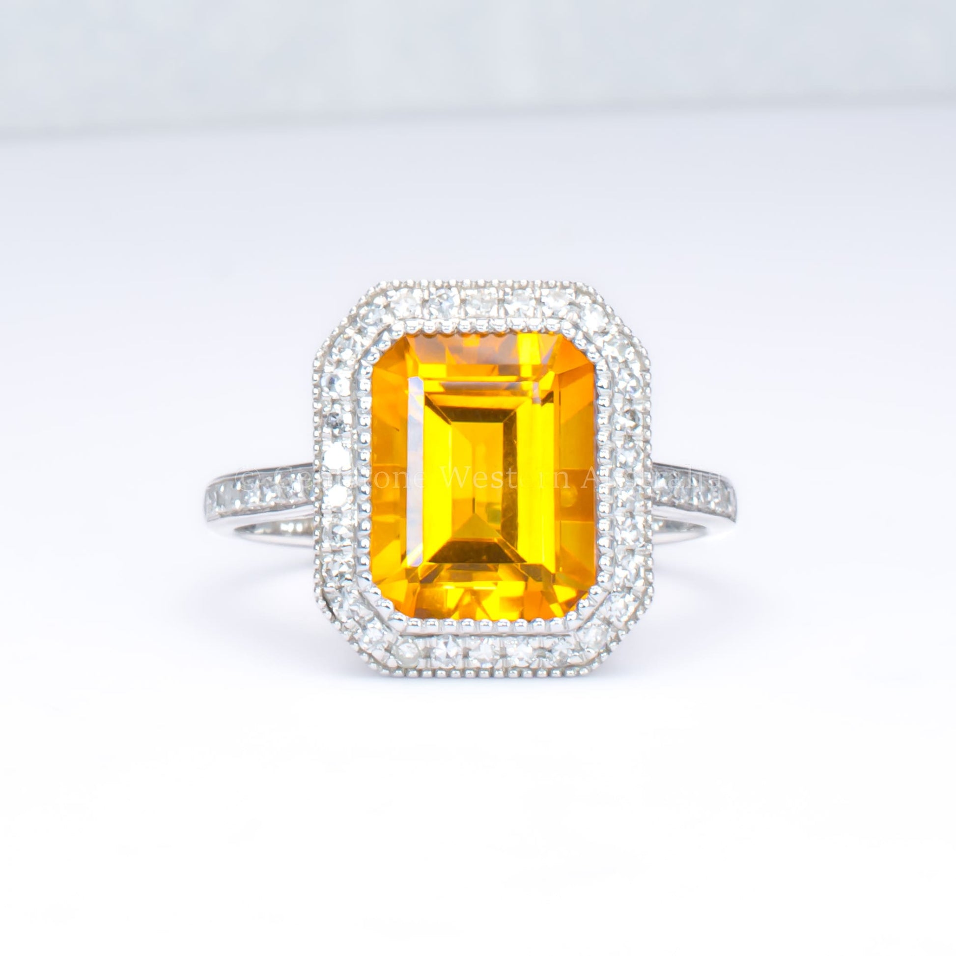 Citrine and diamond halo ring in 18K white gold in light gray background