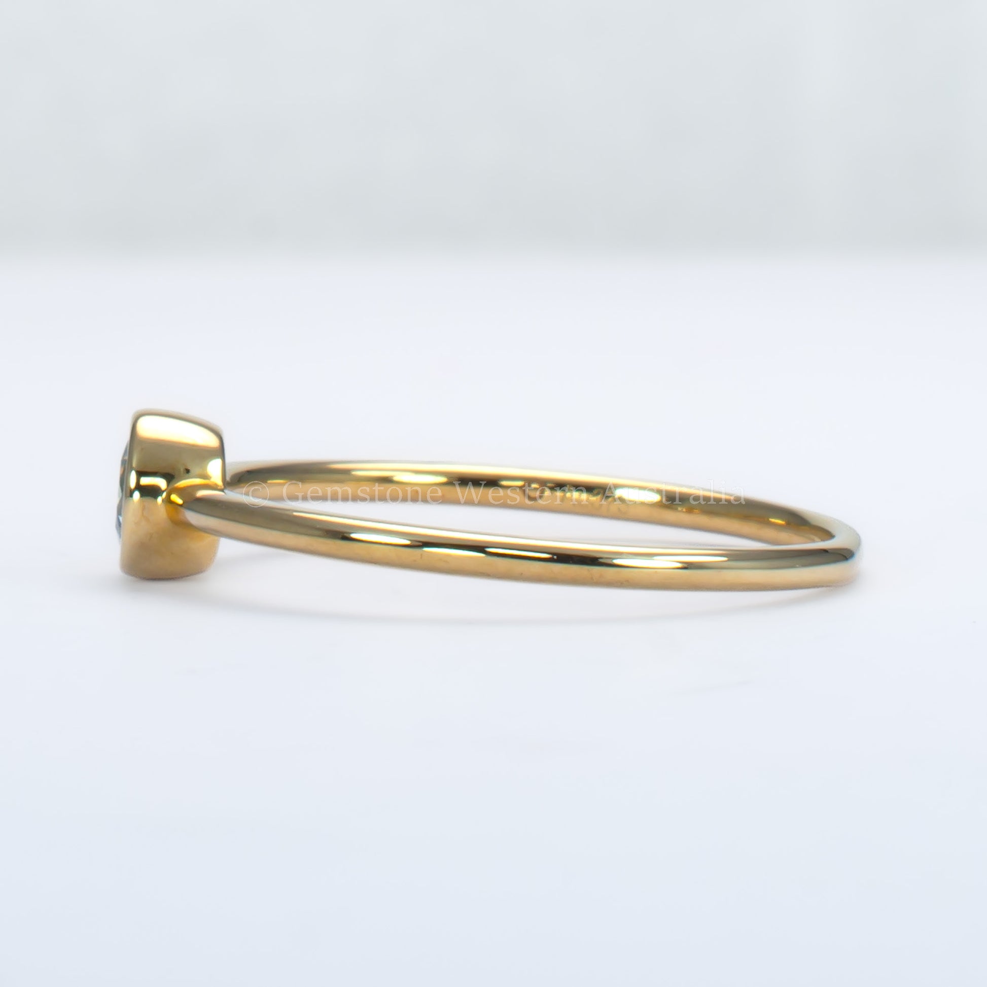 side view of aquamarine yellow gold ring in light gray background