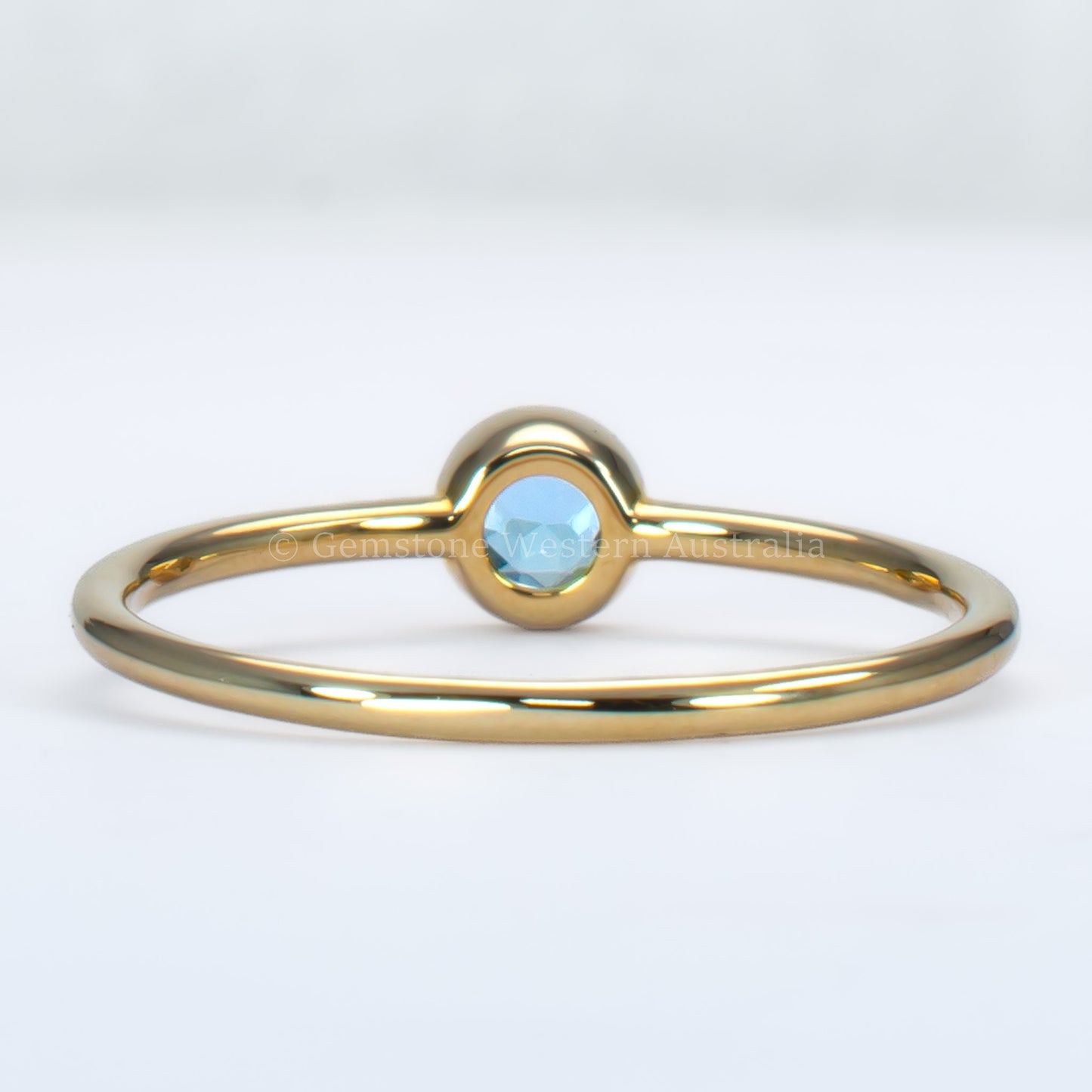 back view of aquamarine yellow gold ring in light gray background