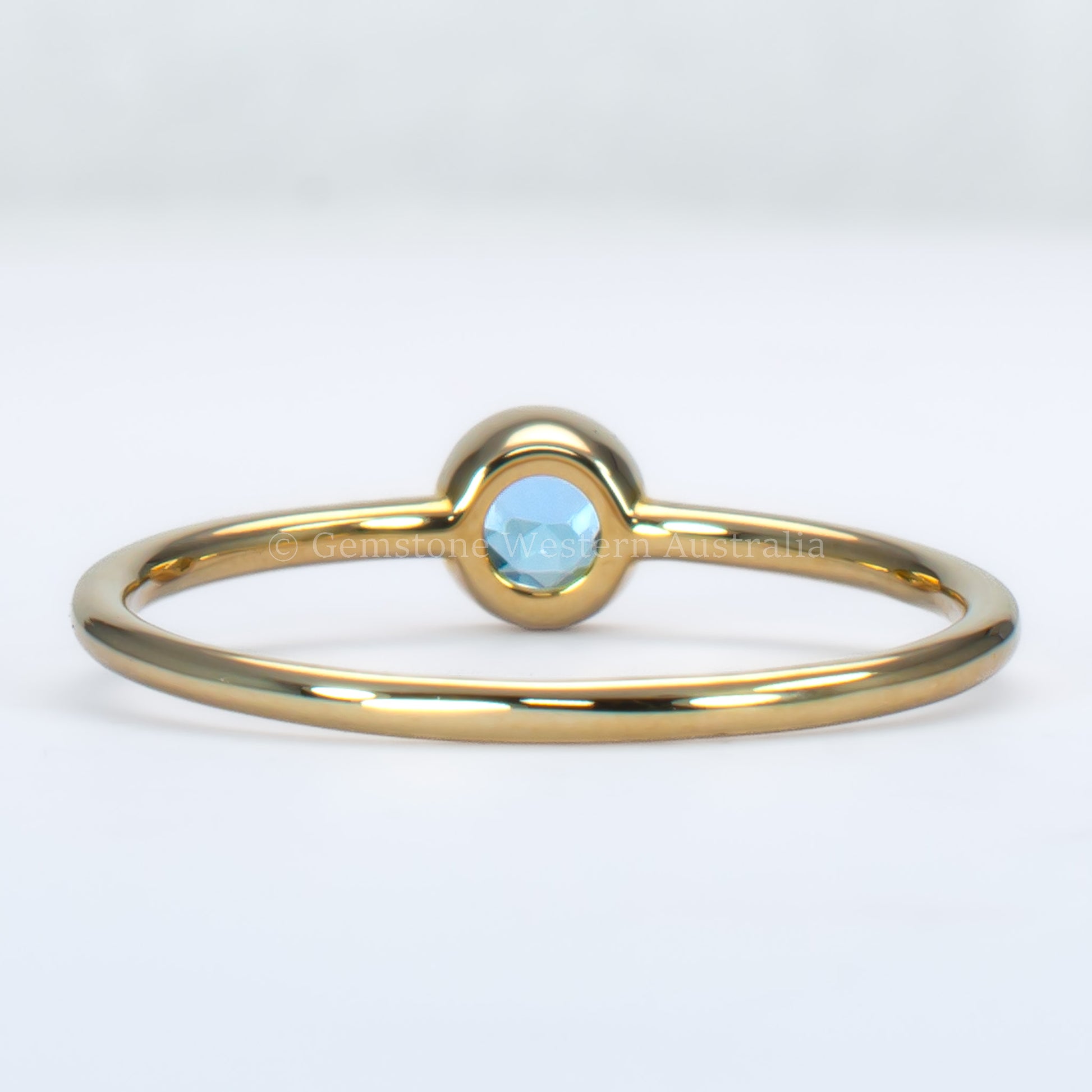 back view of aquamarine yellow gold ring in light gray background