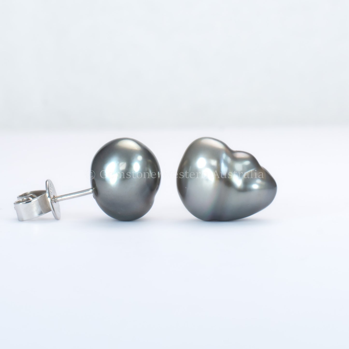 side and front view of Tahitian pearl stud earrings on a gray background