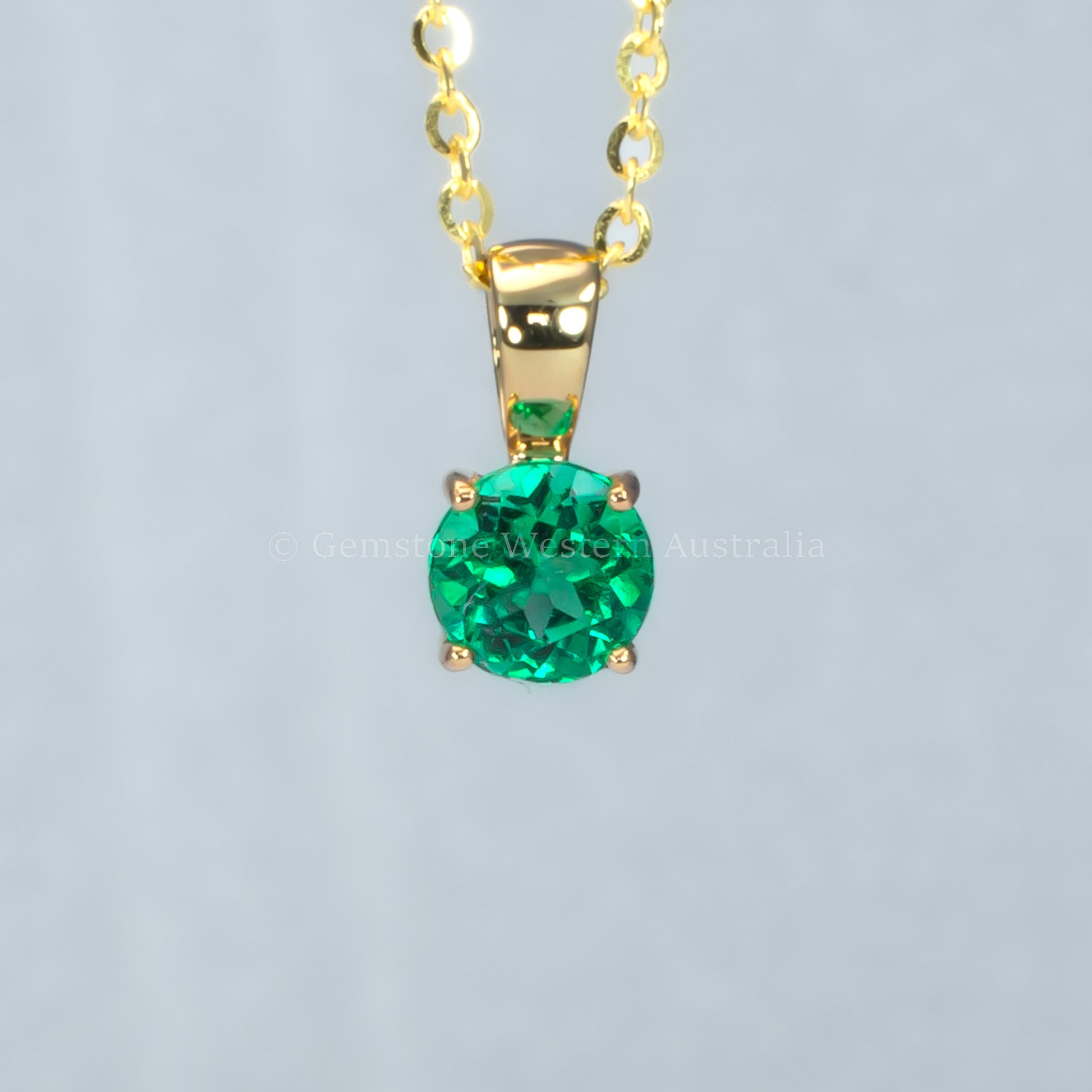 Colombian emerald gold pendant in gray background
